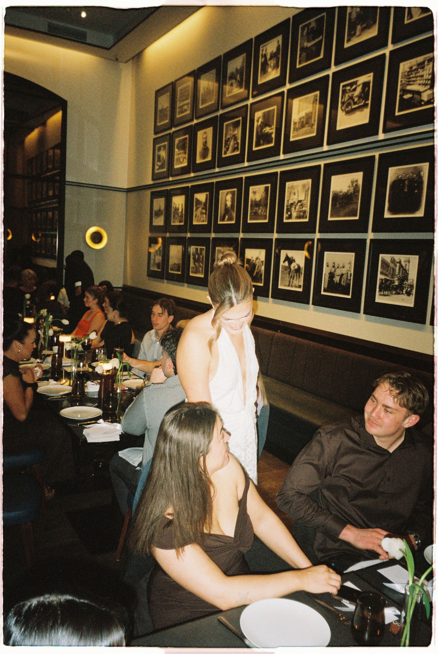 Guests dine at upscale restaurant with framed black and white photos lining the walls.