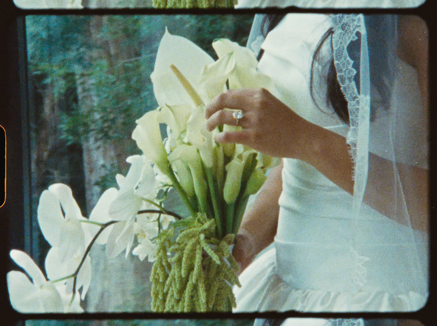 Bride holding a bouquet of white calla lilies with a diamond ring visible on her hand.