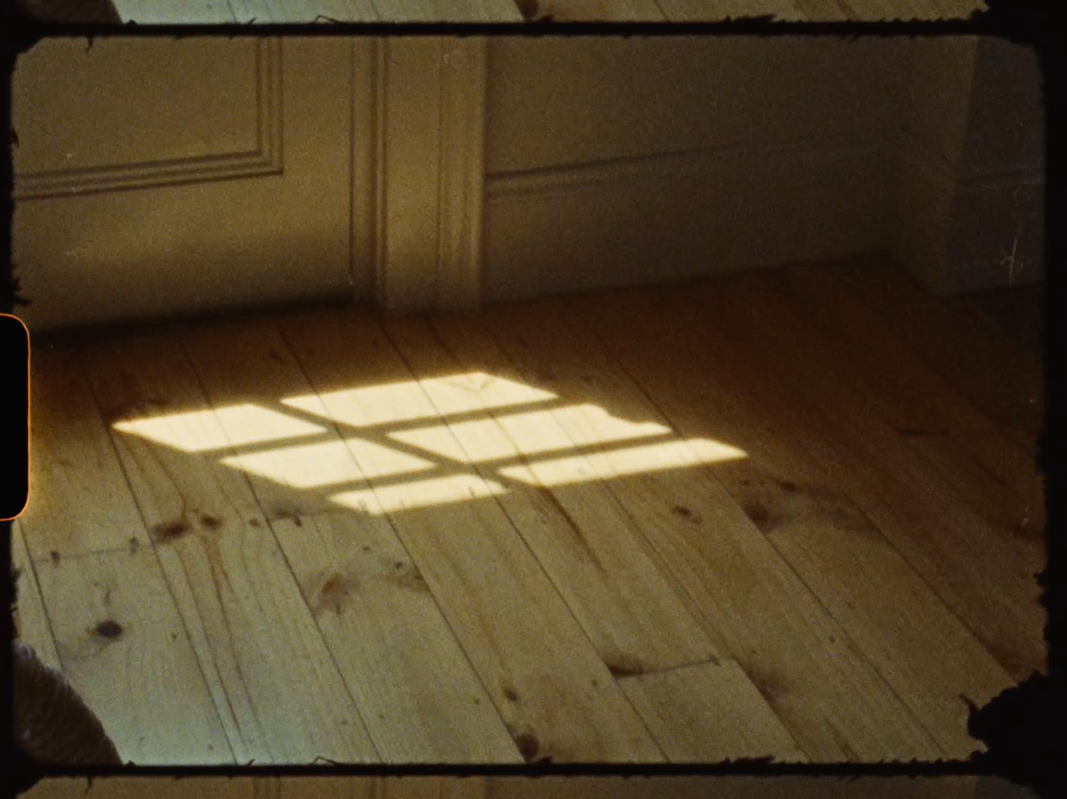 Vintage film-style photo of warm sunlight casting window shadows on rustic wooden floorboards.