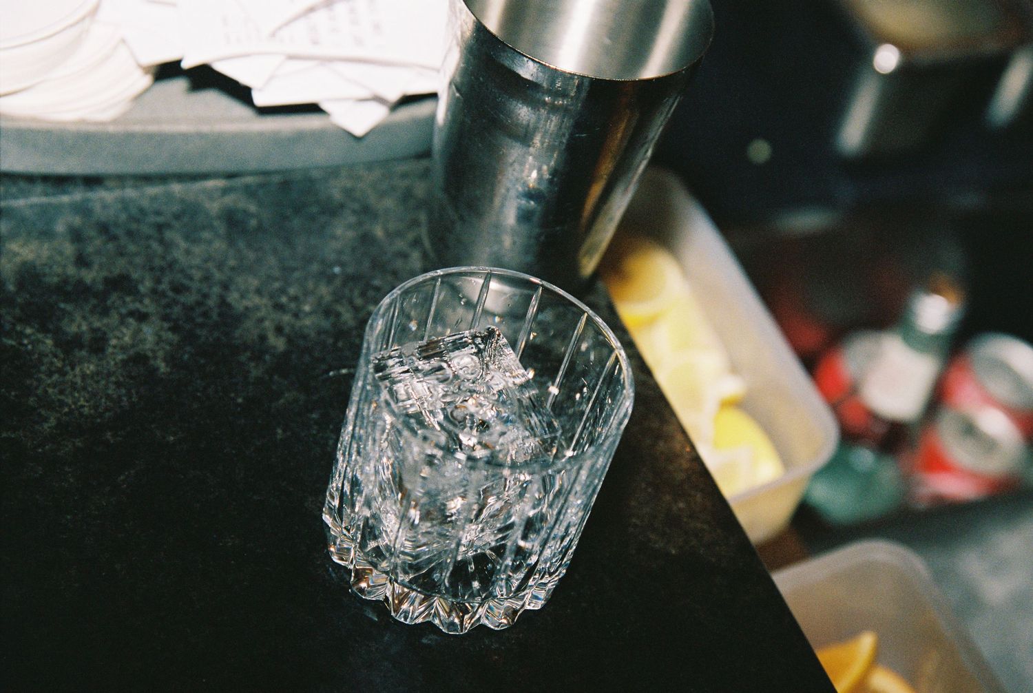 Crystal rocks glass filled with ice next to a cocktail shaker at a wedding bar.