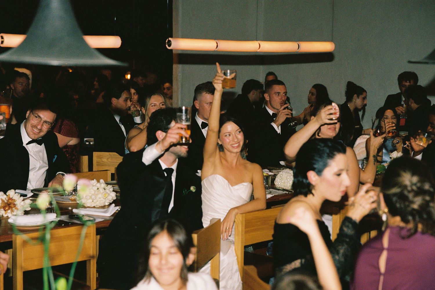 Bride and groom toasting with guests at elegant wedding reception dinner.