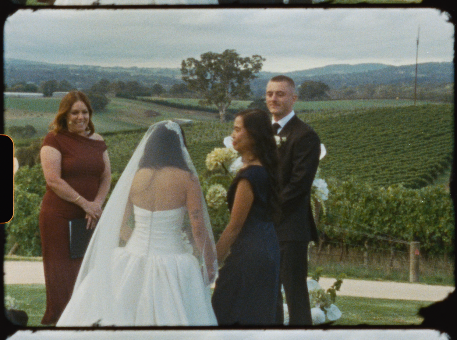 Bride meeting groom at outdoor vineyard wedding ceremony with rolling hills in background.