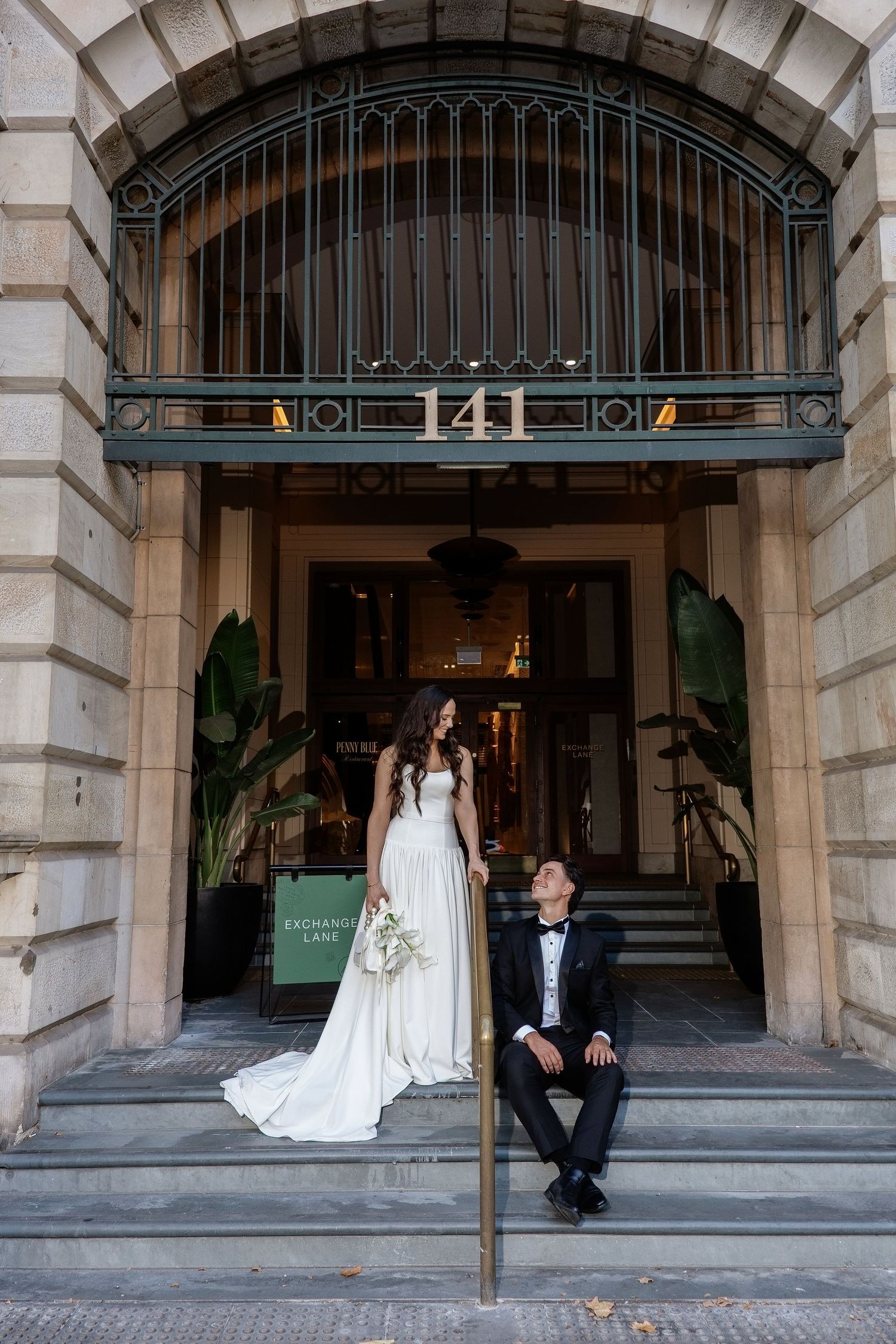 Bride and groom sharing a romantic glance on the steps of building 141.
