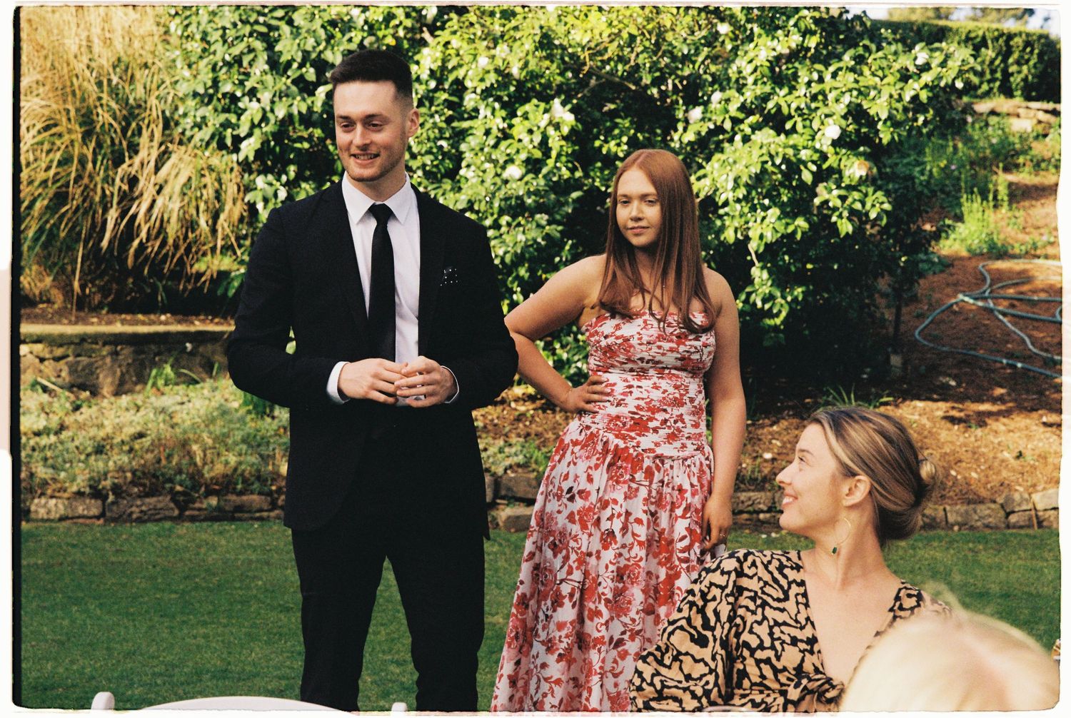 Guests in formal attire socializing outdoors at a garden wedding reception.
