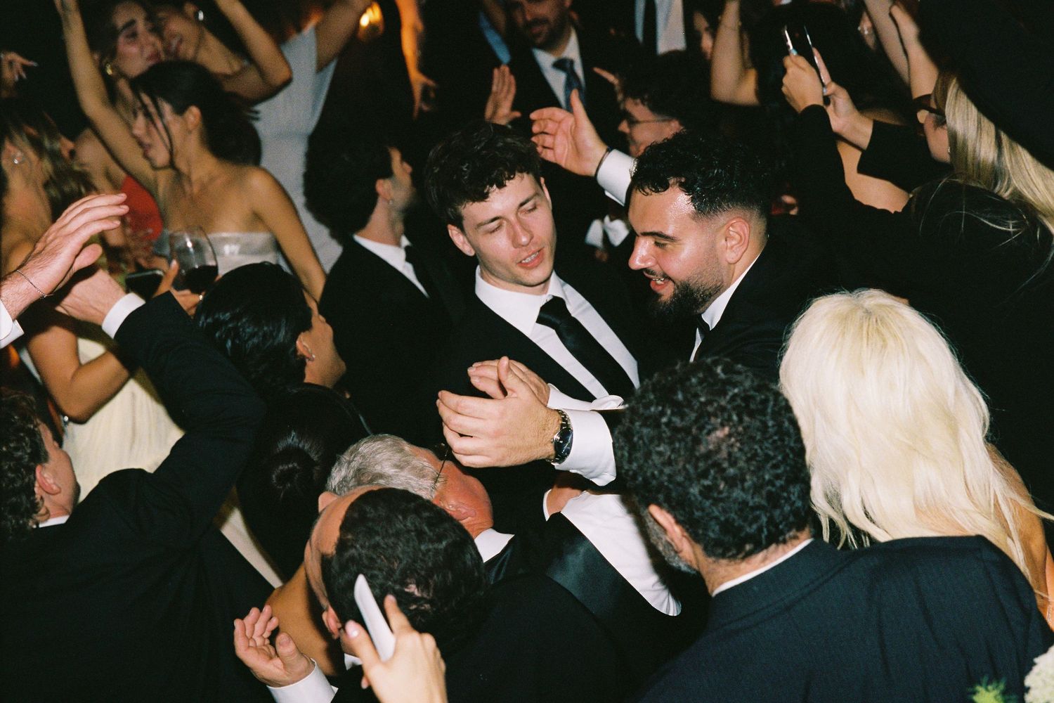 Groom celebrating with friends on a lively wedding reception dance floor.