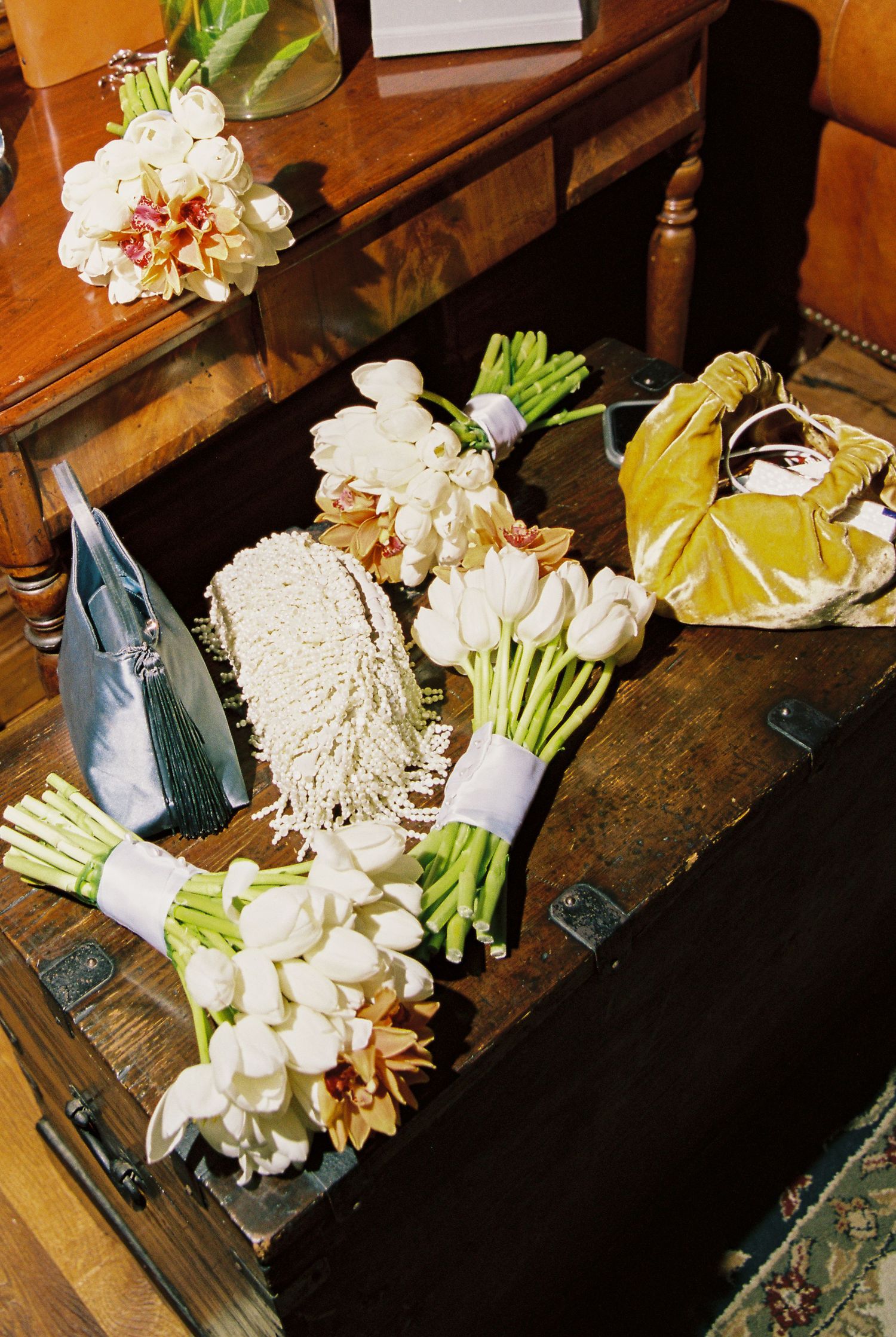 Wedding bouquets of white tulips and orchids arranged on antique wooden chest.