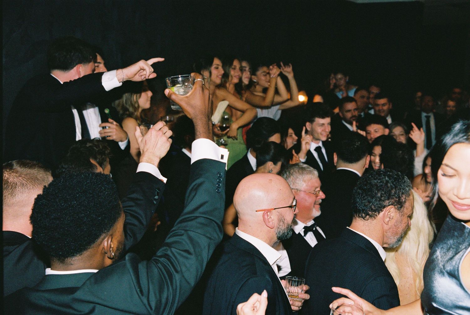 Energetic wedding reception dance floor with guests celebrating in formal attire.