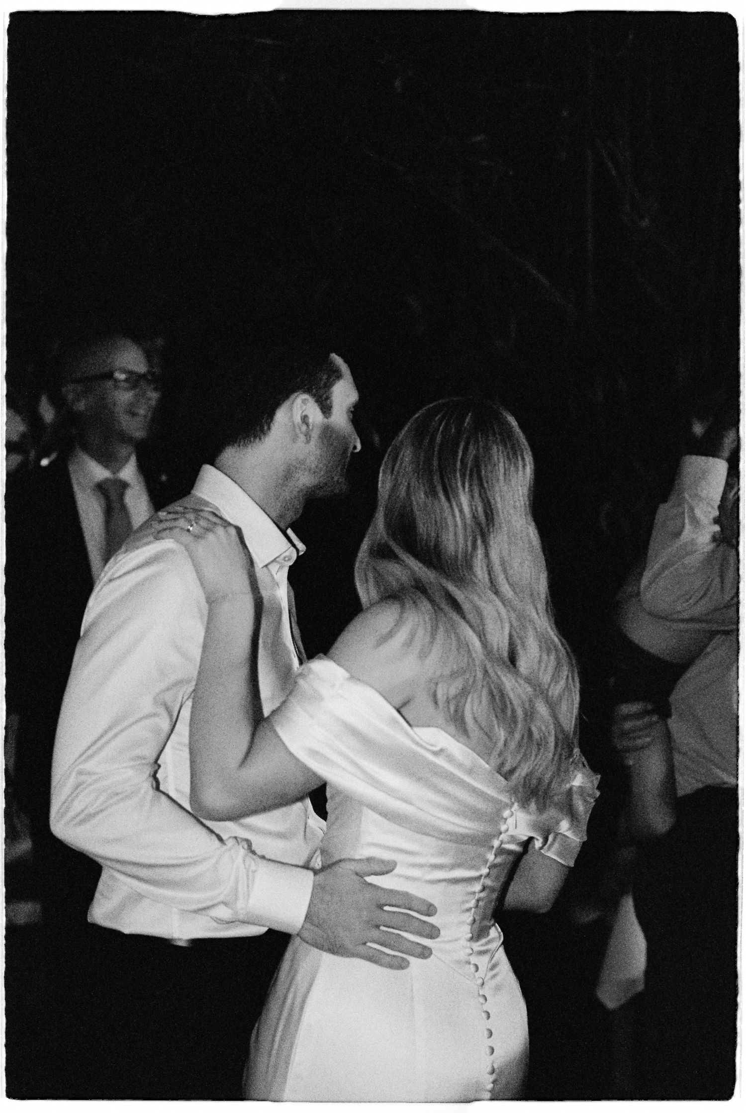 Bride and groom sharing their first dance at wedding reception in black and white photo.