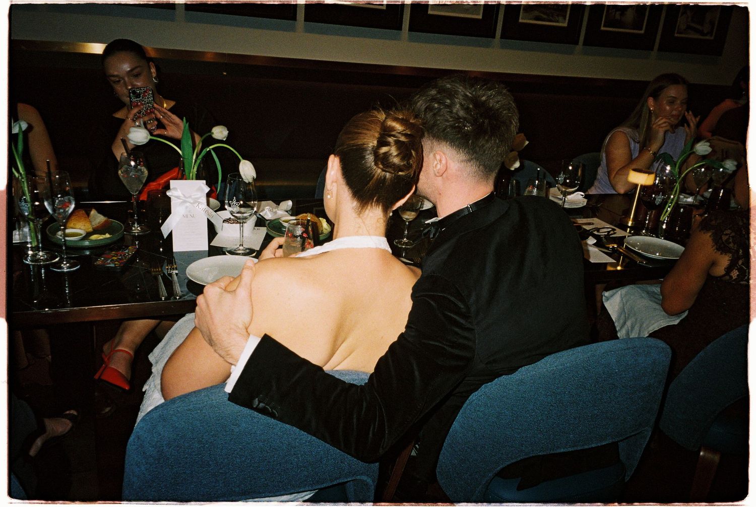Couple sharing an intimate moment at a wedding reception dinner table in a dimly lit venue.