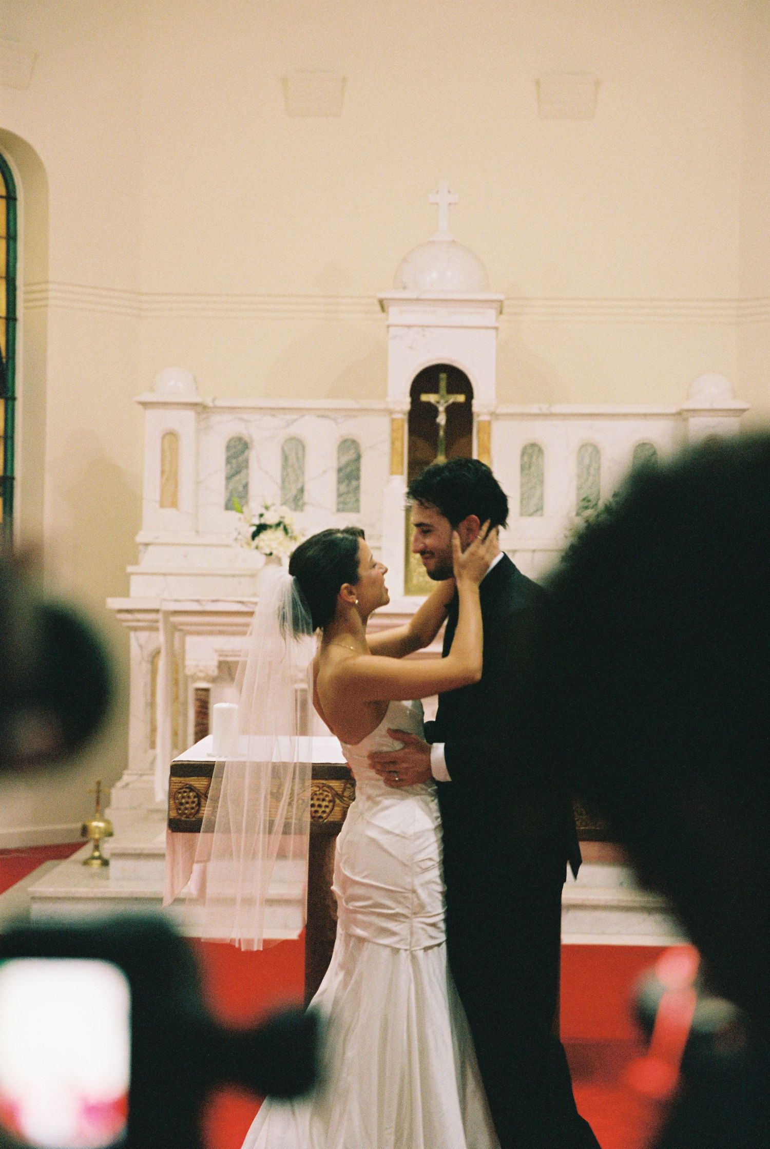 Bride and groom share romantic first dance at church altar, bride wearing mermaid gown and veil.