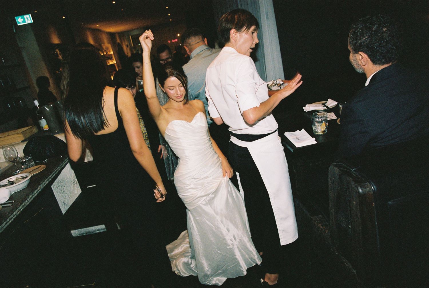 Bride in strapless gown dancing joyfully at wedding reception with guests.