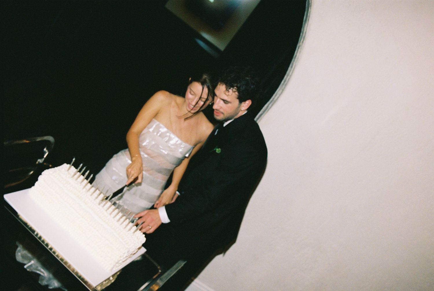 Aerial view of bride and groom cutting their white wedding cake together at their reception.