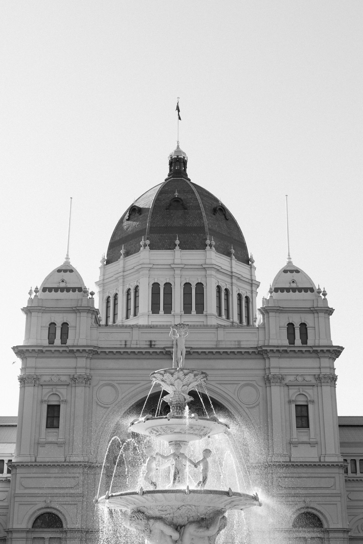 Black and white photo of Royal Exhibition Building Melbourne dome with ornate fountain in foreground.