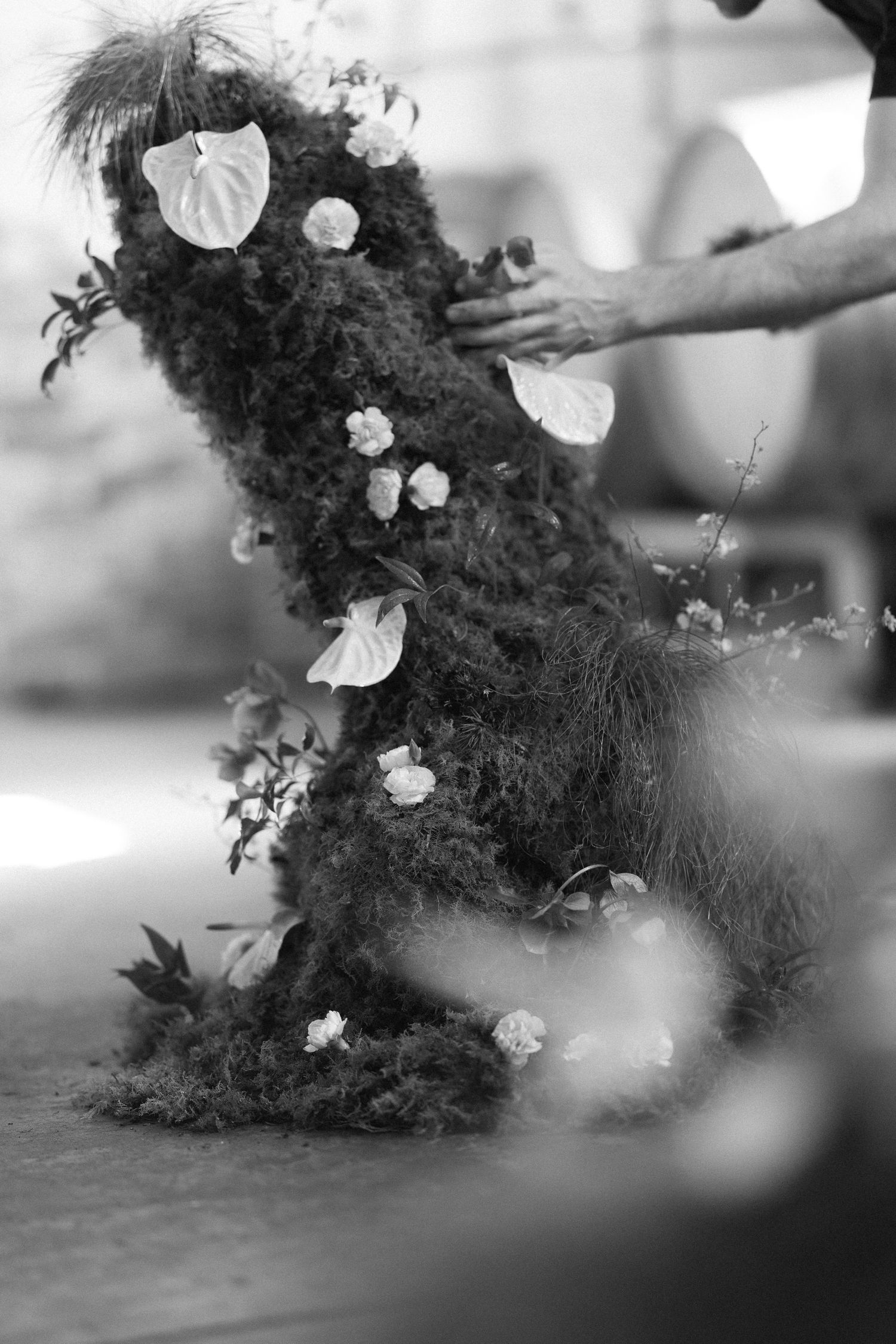 Black and white detail of moss and flower floral installation being arranged for wedding ceremony.