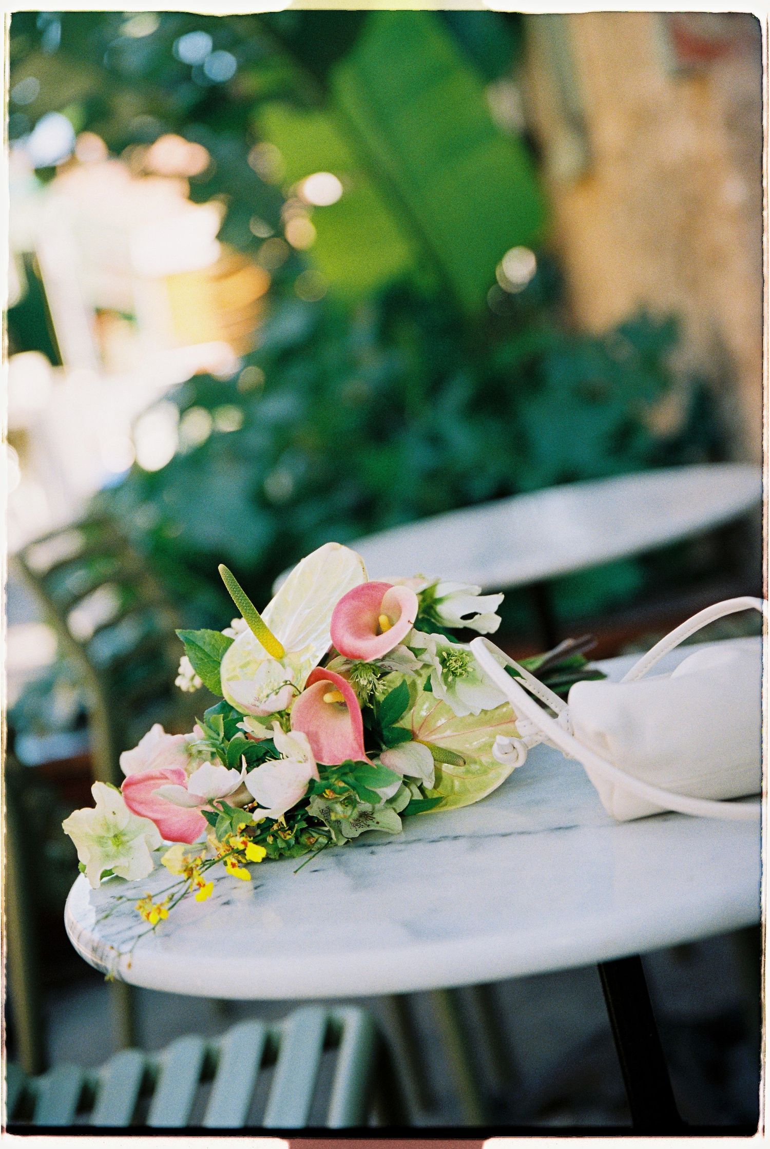 Elegant wedding bouquet with pink calla lilies and white flowers on a marble table outdoors.