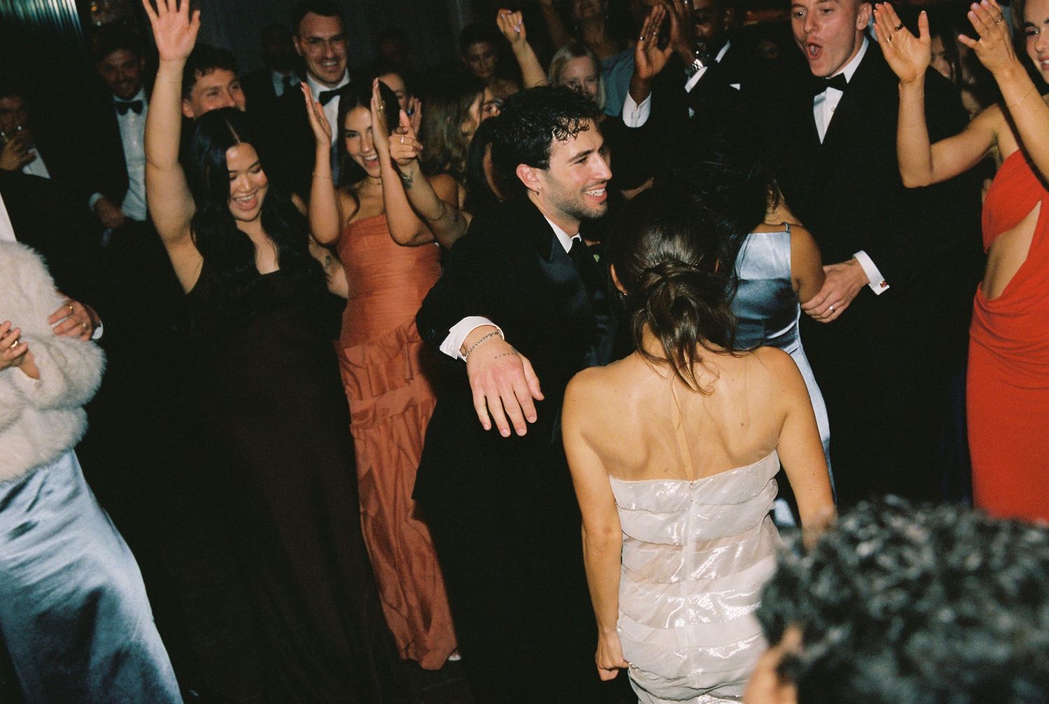 Guests dancing joyfully on the dance floor at a lively wedding reception.