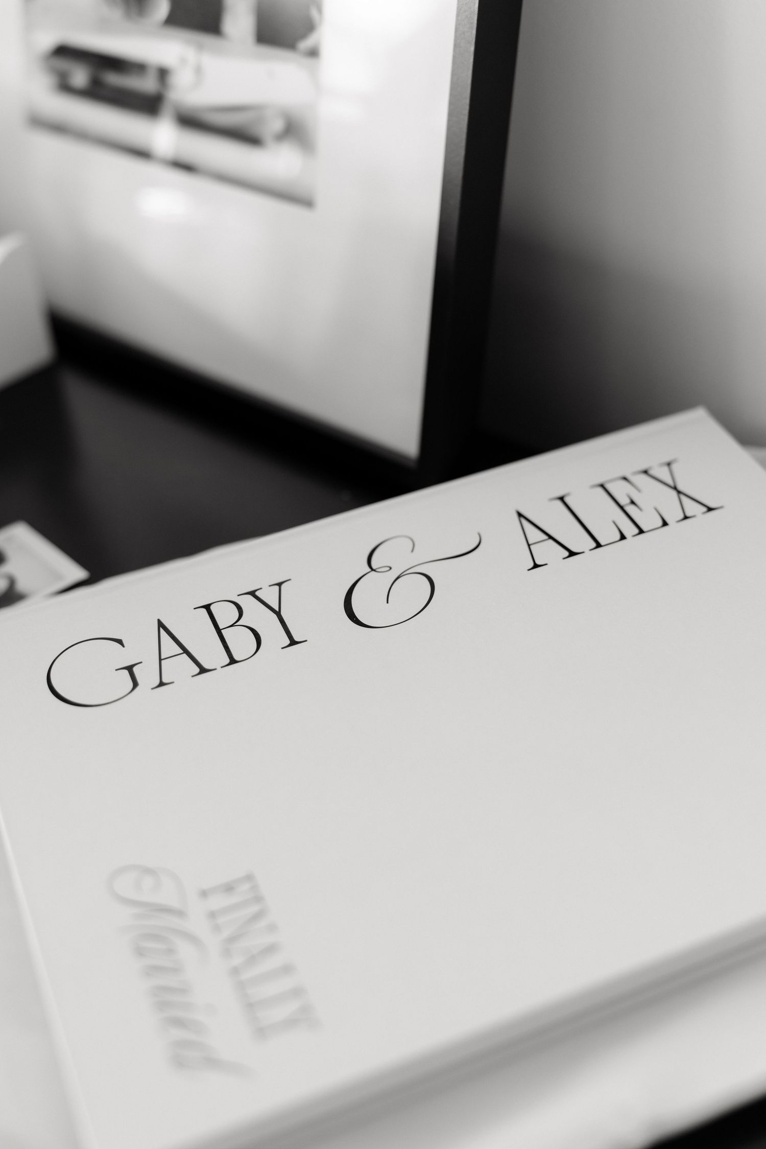 Black and white close-up of a wedding guest book embossed with the names Gaby and Alex.