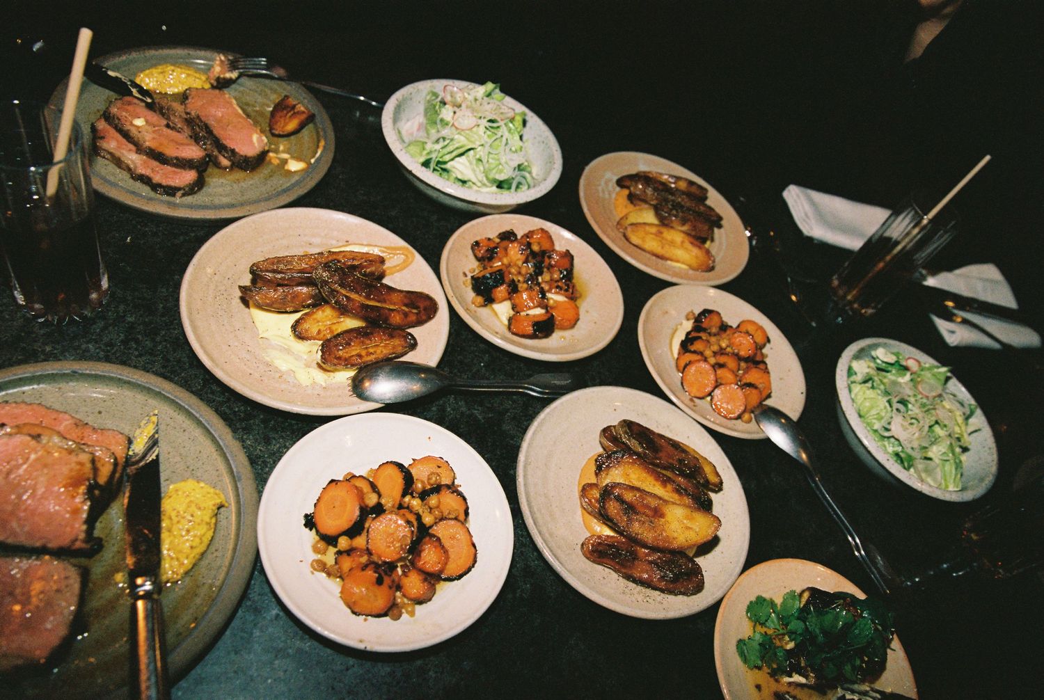 Overhead view of a wedding reception dinner spread featuring meat, vegetables, and salads.
