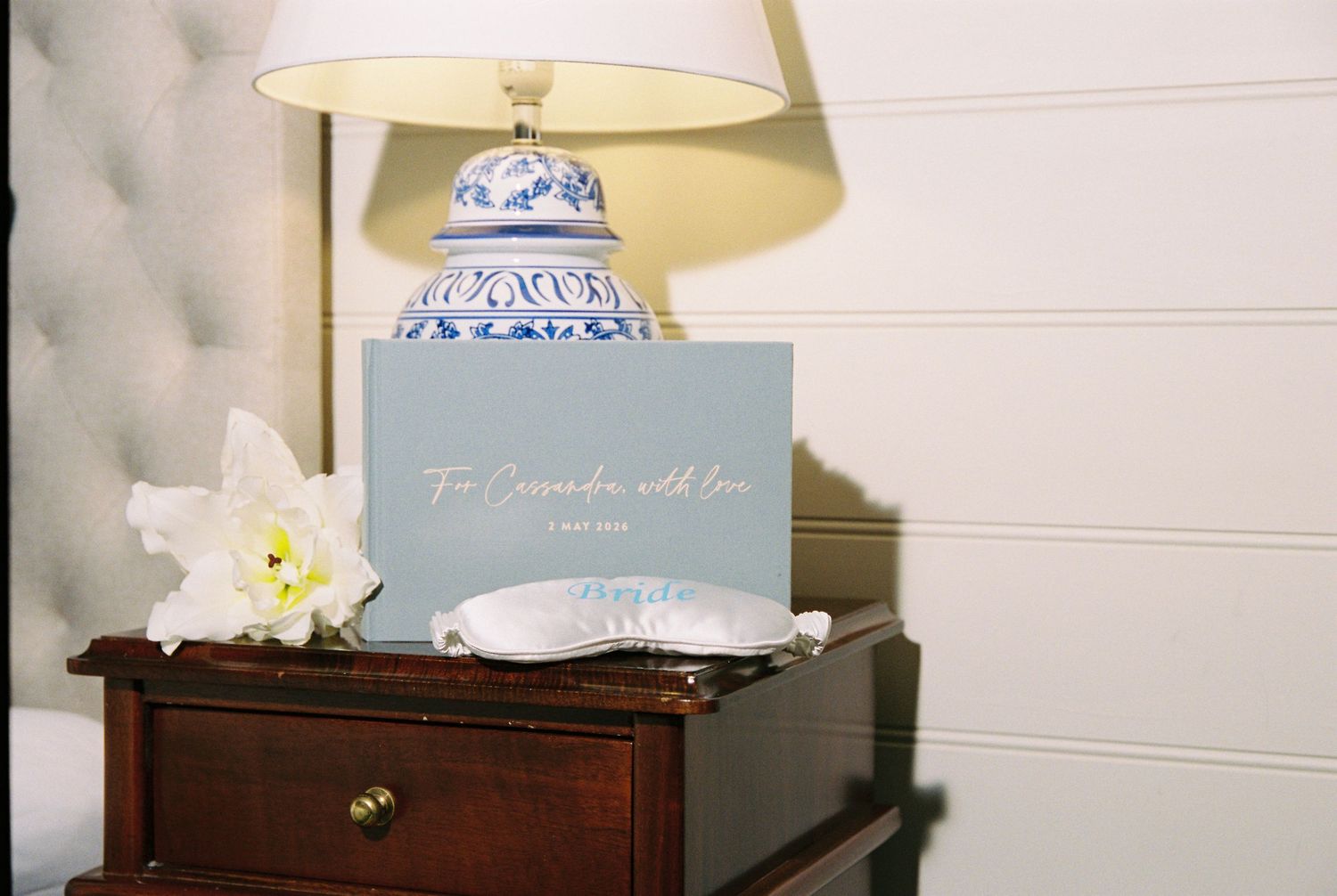 Wedding gift card reading To Cassandra with love on a bedside table with a blue and white ceramic lamp.