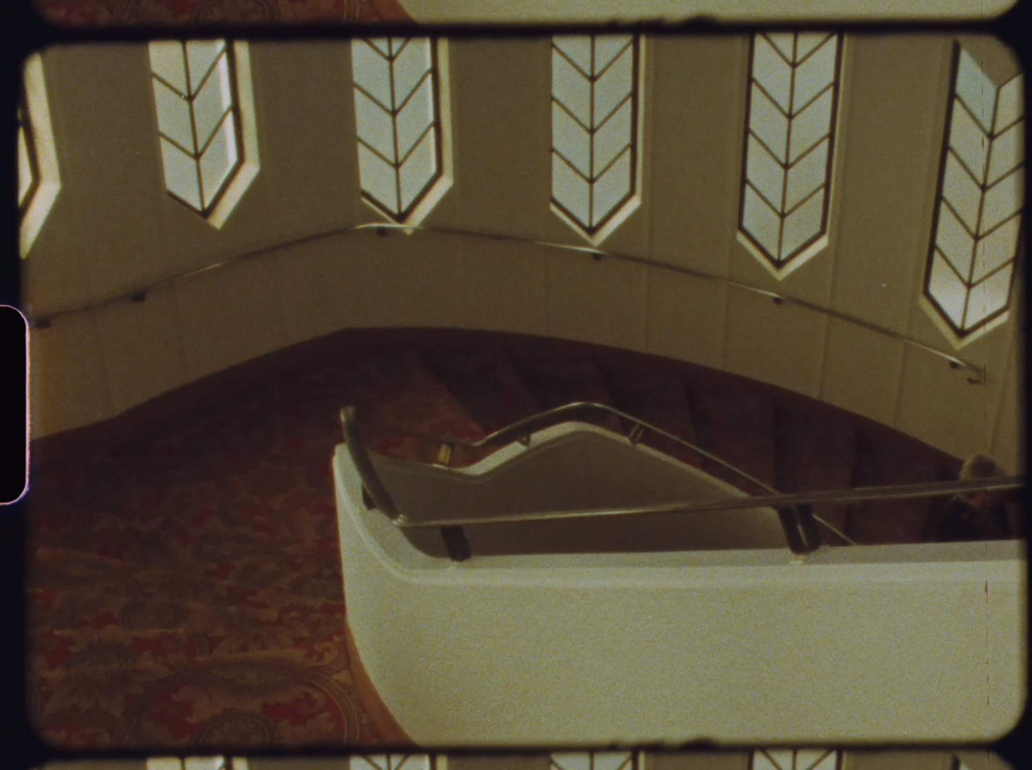 An aerial view of a curved staircase with decorative arched windows above.