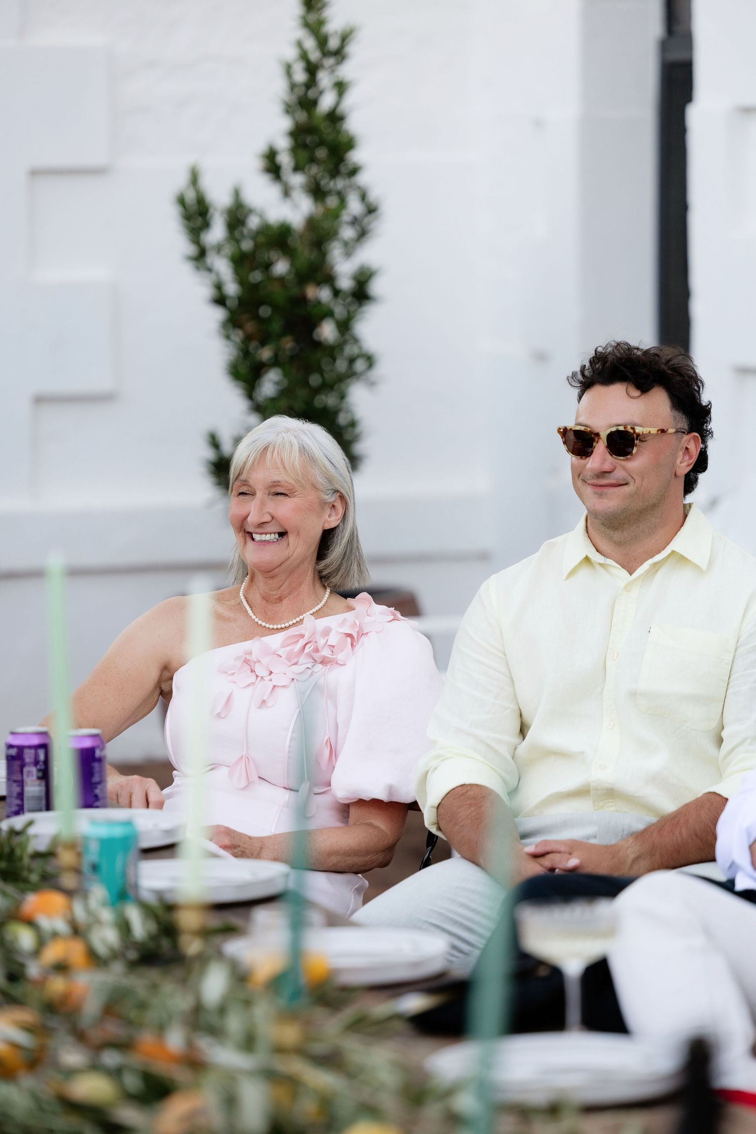 Smiling mother of bride seated with guest at elegant outdoor wedding reception.