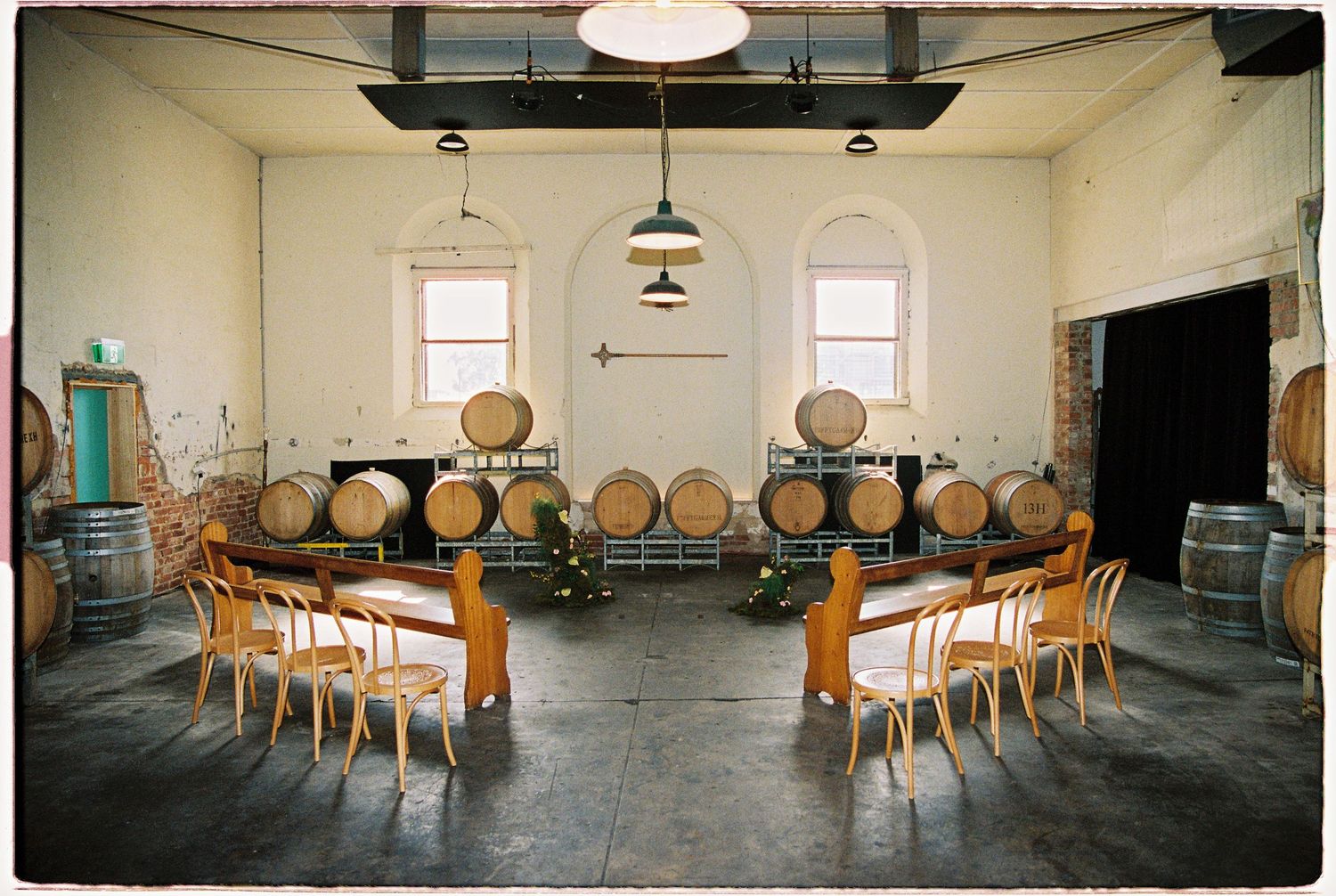 Rustic winery barrel room set up for an intimate event with wooden chairs arranged in a circle around a floral centerpiece.
