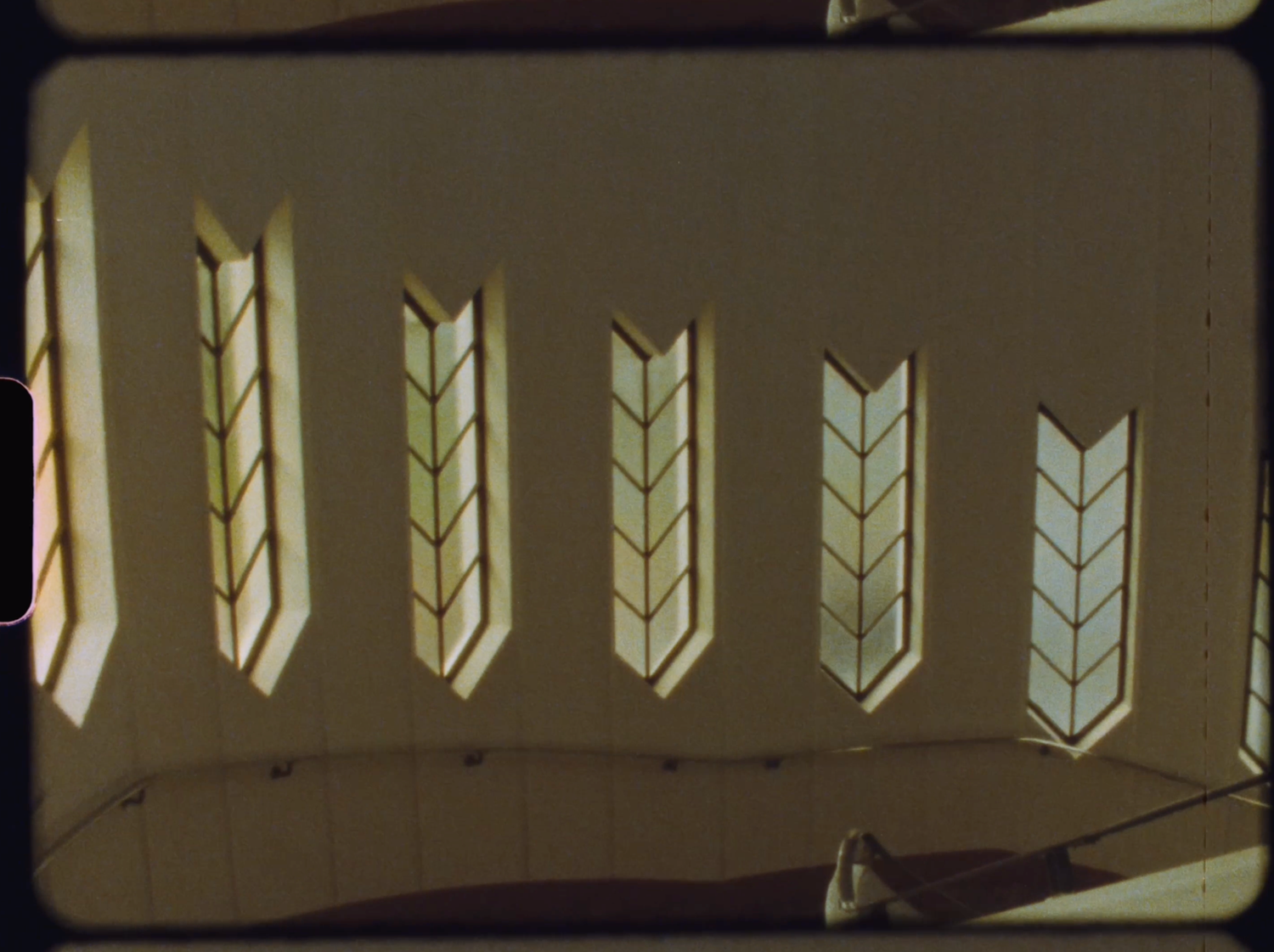 Decorative arrow-shaped stained glass windows casting warm light on a curved ceiling.