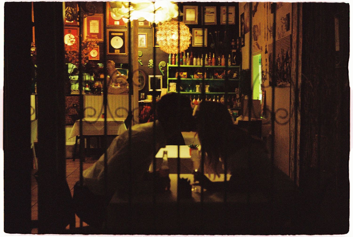 Couple dining in warmly lit vintage restaurant with eclectic decor and ambient golden lighting.