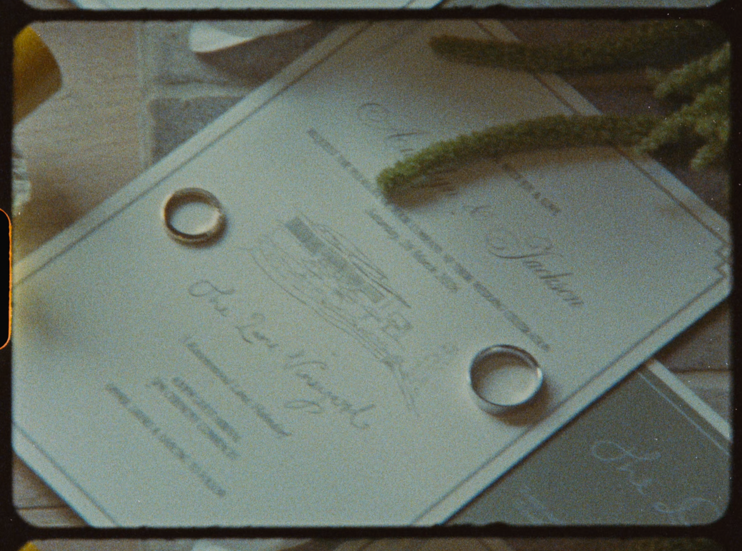 Two gold wedding bands resting on elegant wedding invitation with cursive script.