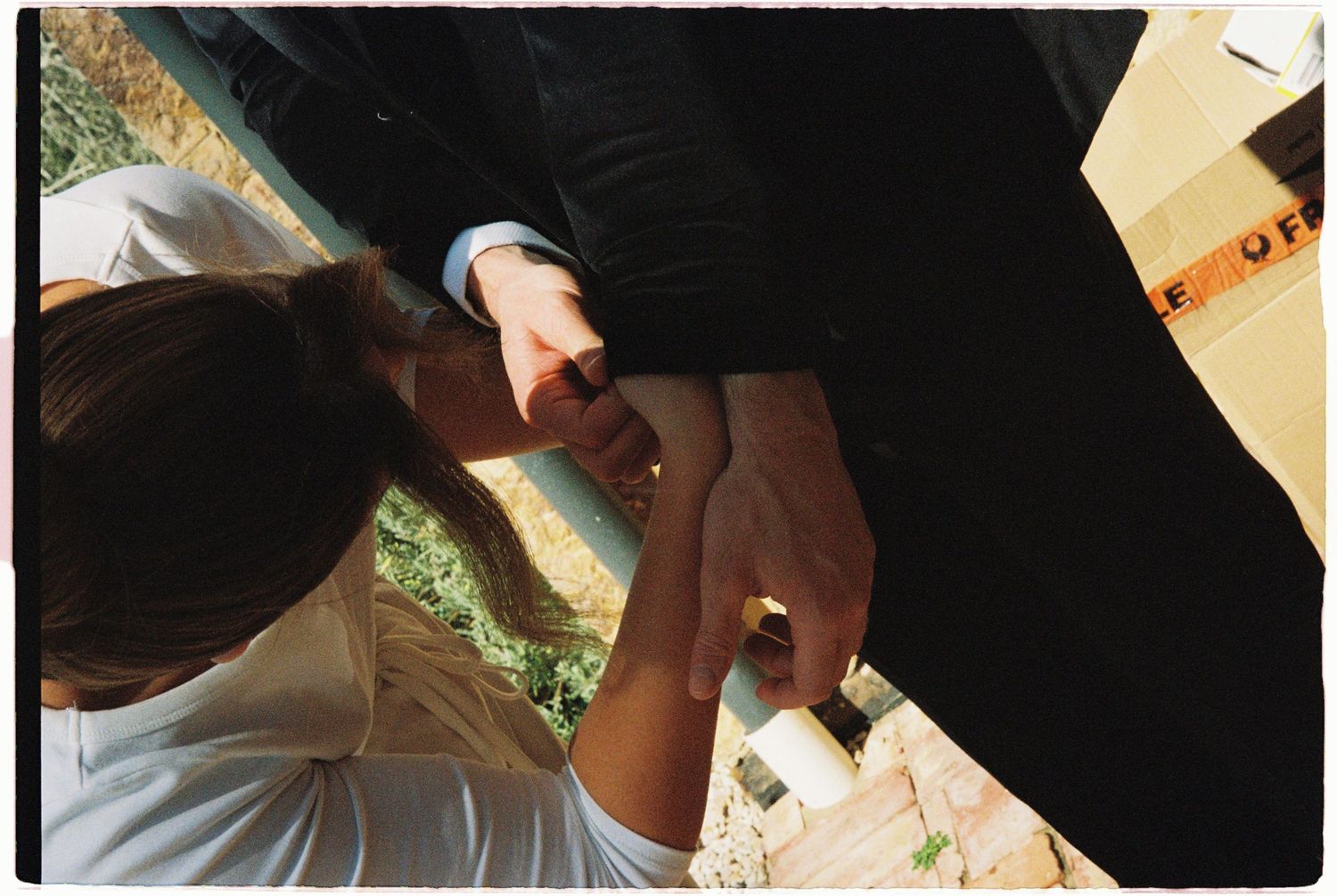 Close-up of bride and groom holding hands during intimate outdoor wedding ring exchange ceremony.