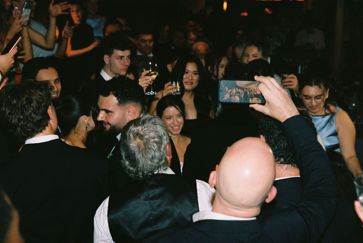 Crowd of wedding guests gather and celebrate together on a lively dance floor.
