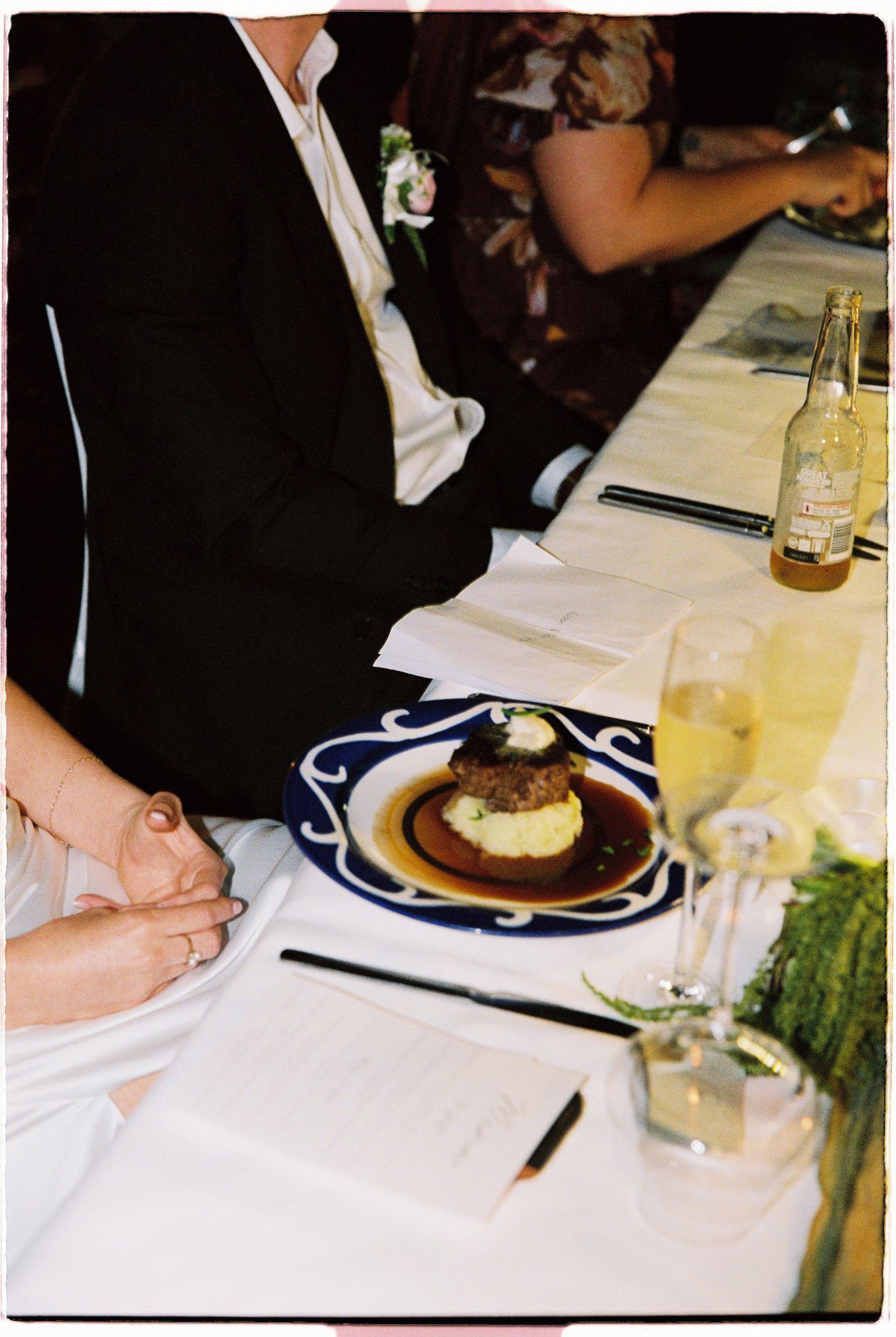 Wedding reception dinner plate with filet mignon and mashed potatoes on blue decorative dish.