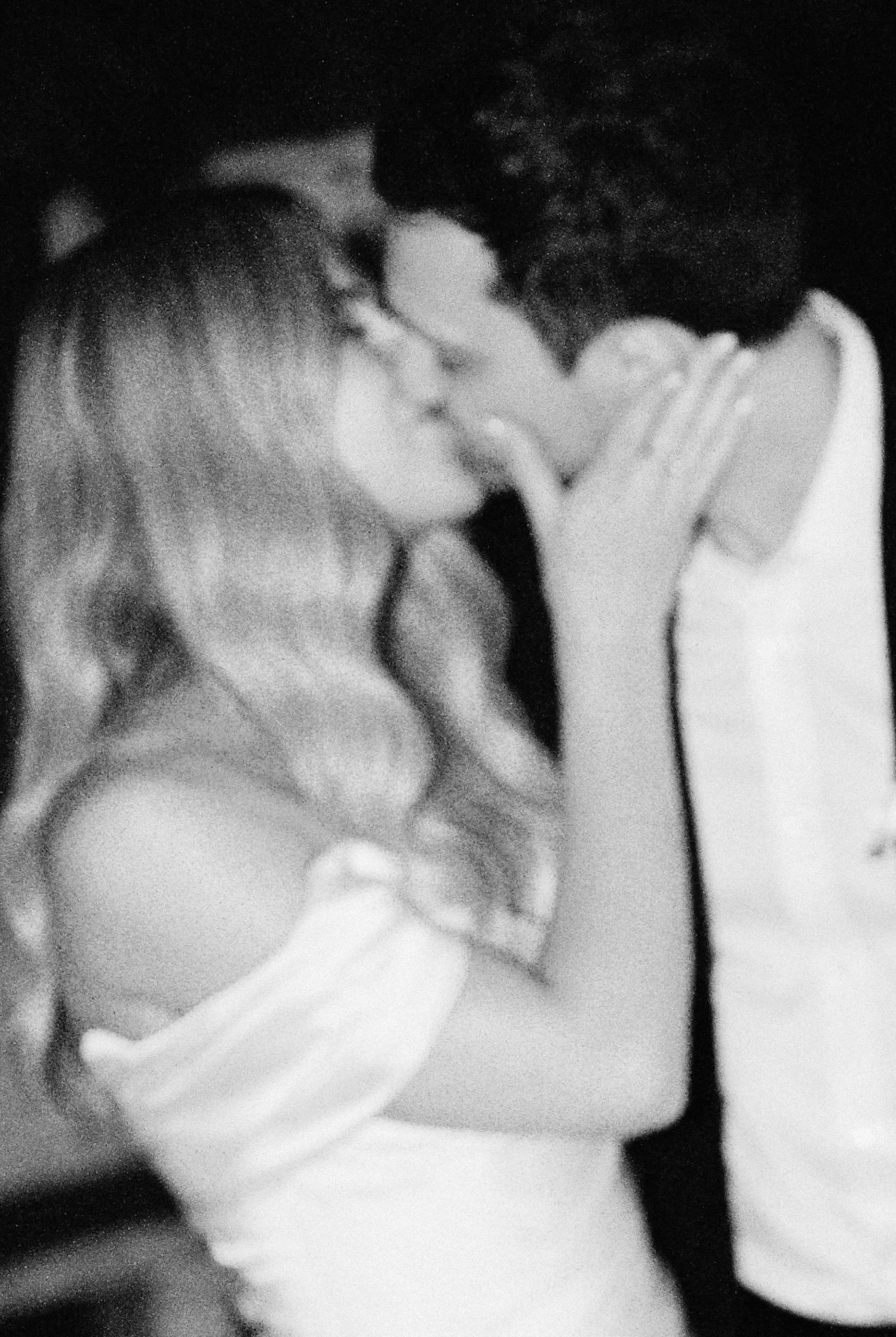 A couple shares a romantic kiss in a dreamy black and white wedding photo.