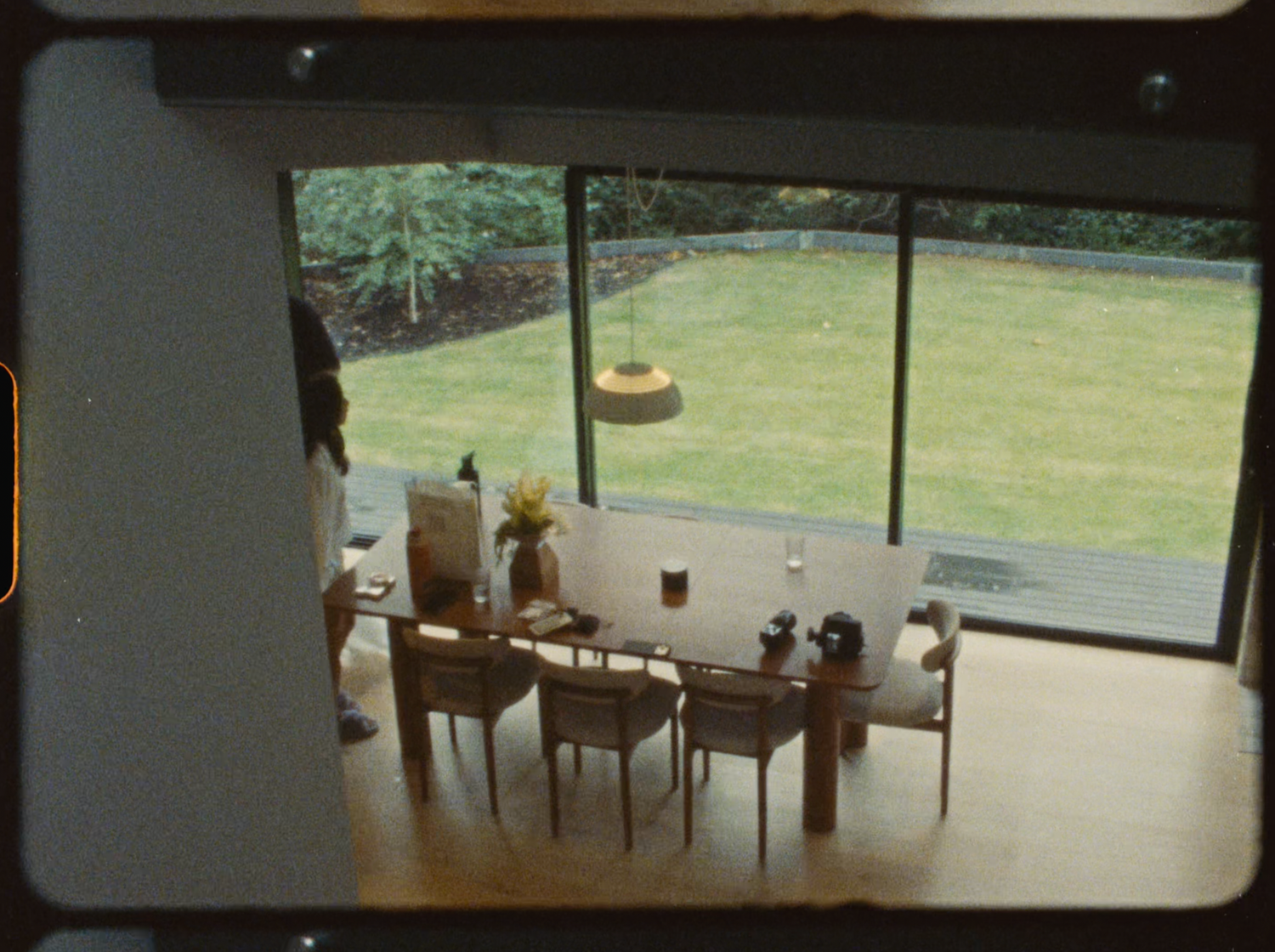 Modern dining room with large floor-to-ceiling windows overlooking a lush green garden.