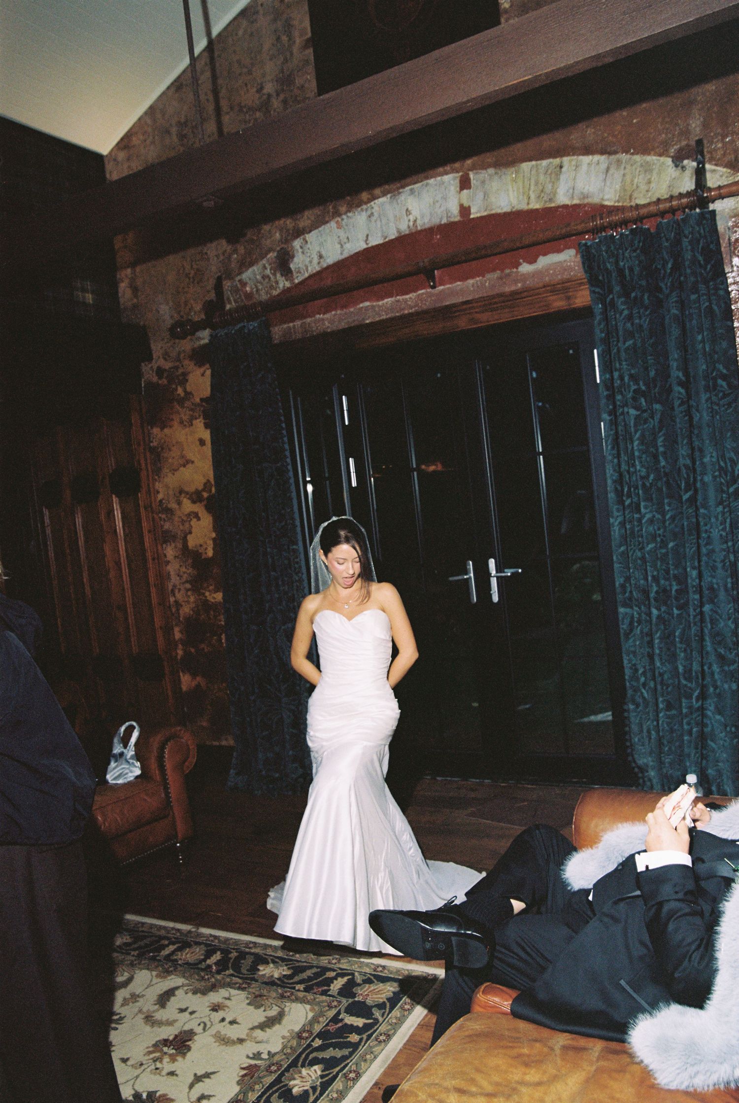 Bride in elegant strapless mermaid wedding gown makes grand entrance into rustic stone wedding venue.