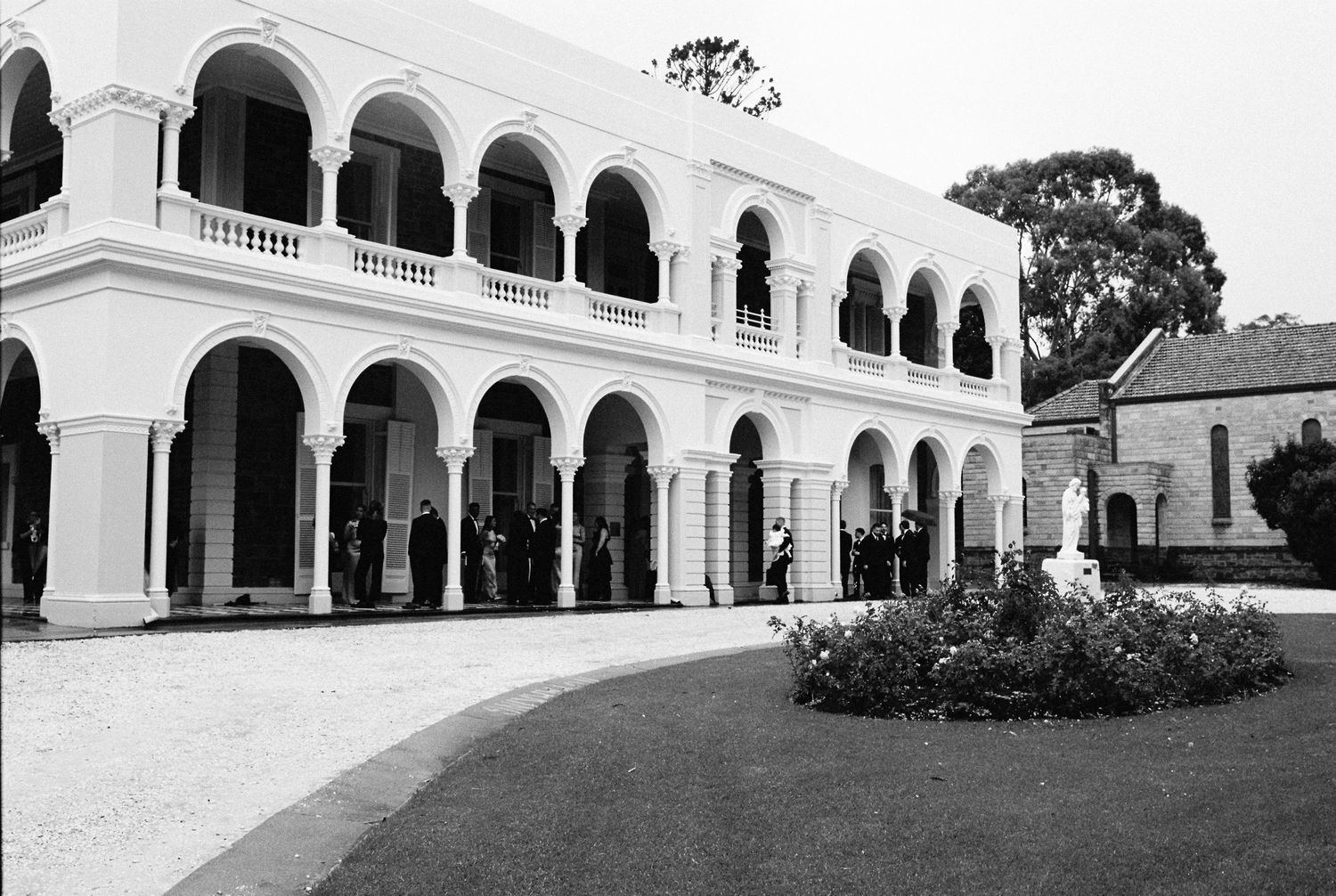 Elegant white colonial building with arched colonnades and balcony in black and white photography.