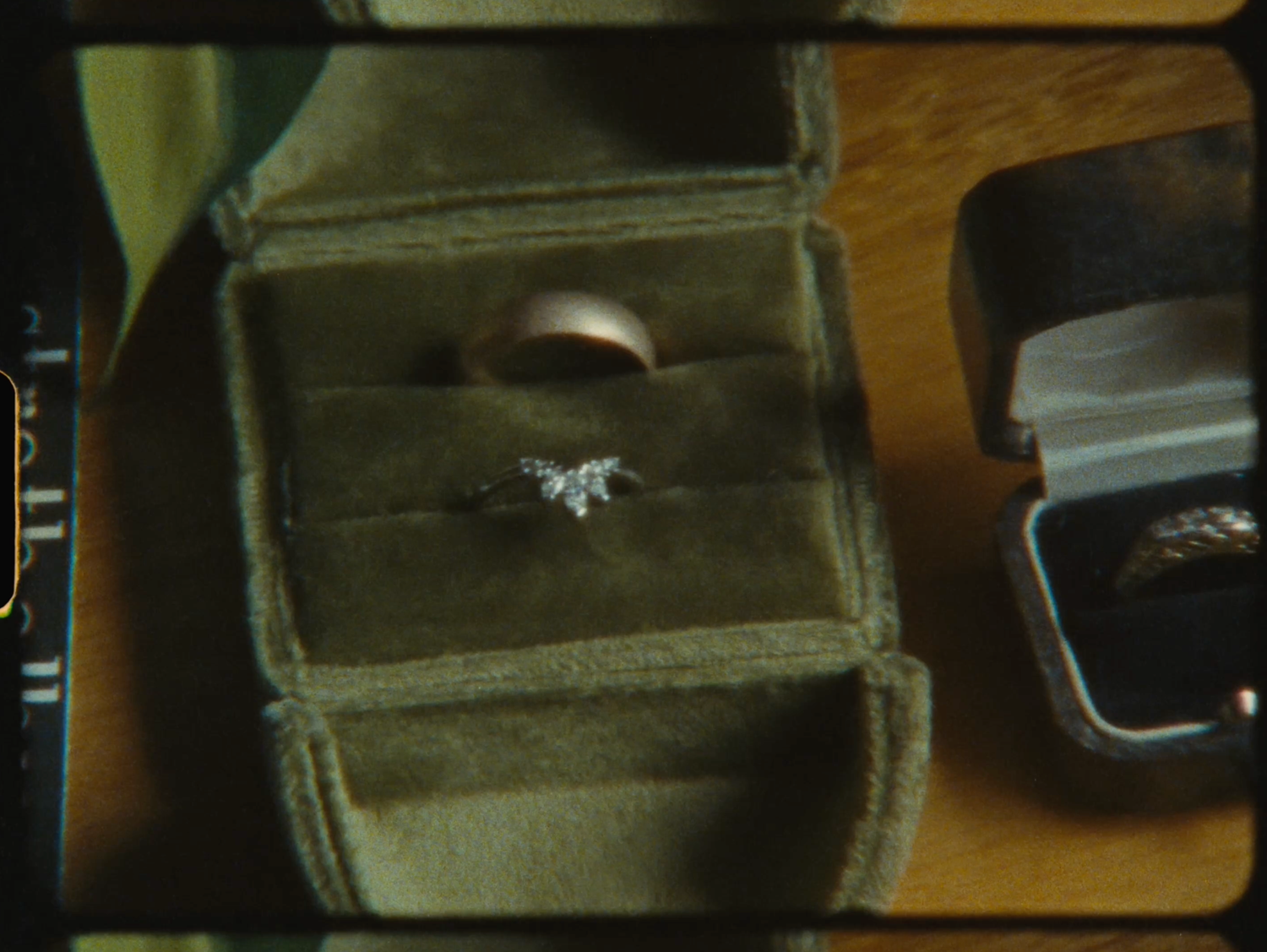 Diamond butterfly engagement ring displayed in a velvet jewelry box alongside other rings on a wooden surface.