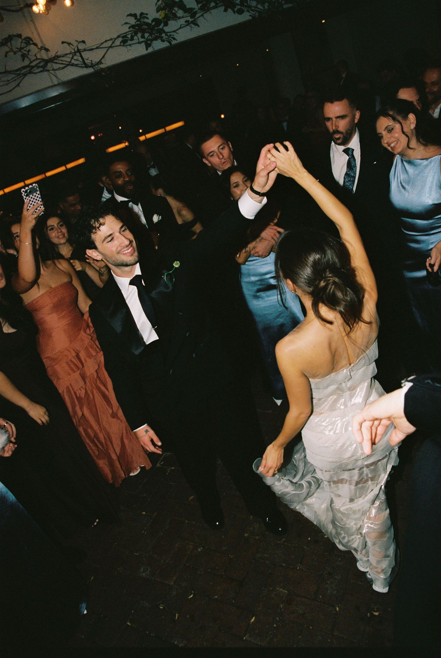 Bride and groom sharing a dance surrounded by guests at a wedding reception.