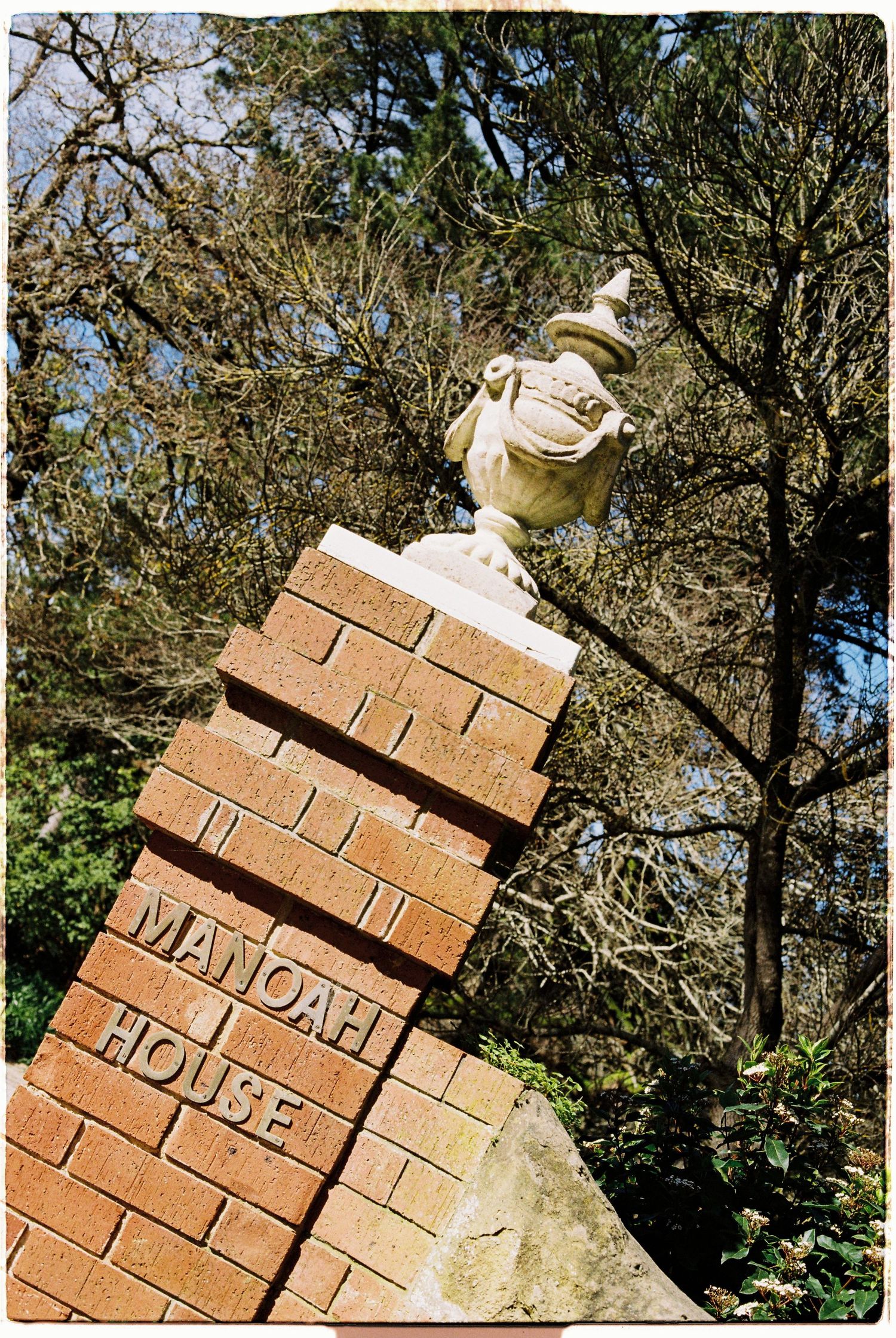 Brick pillar entrance sign reading Manoah House with decorative stone urn at wedding venue.
