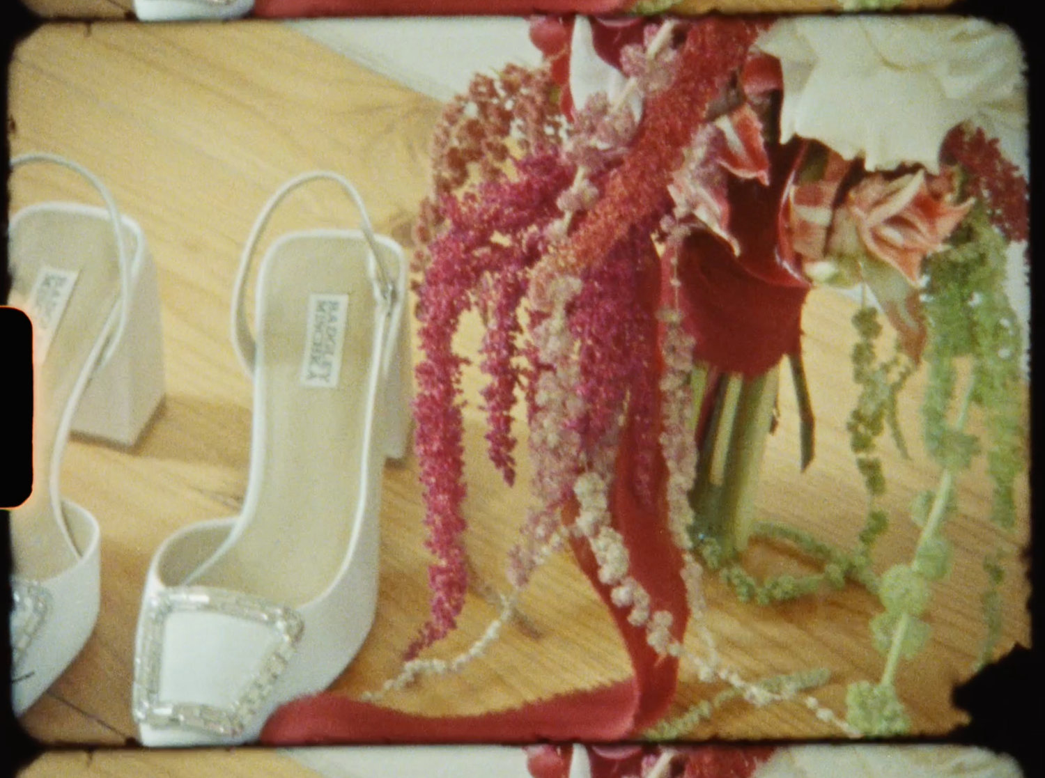 White bridal heels with crystal embellishments displayed beside a lush floral bouquet on wood floor.