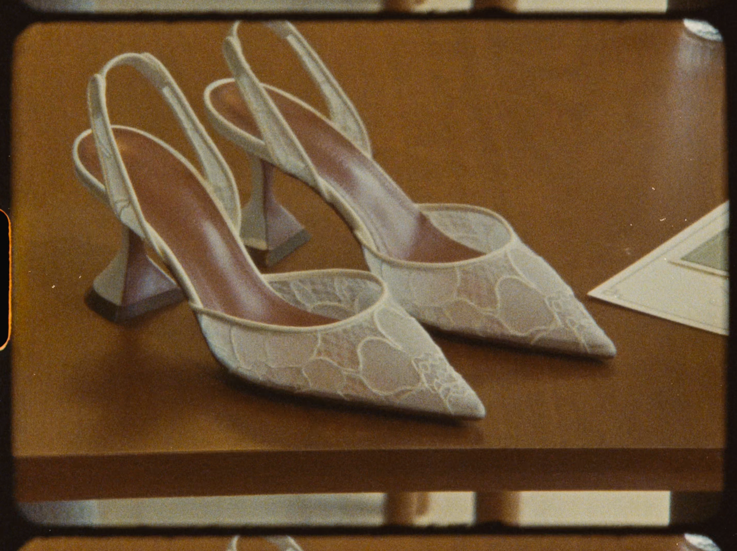 Elegant white lace slingback heels with geometric block heels displayed on wooden surface.