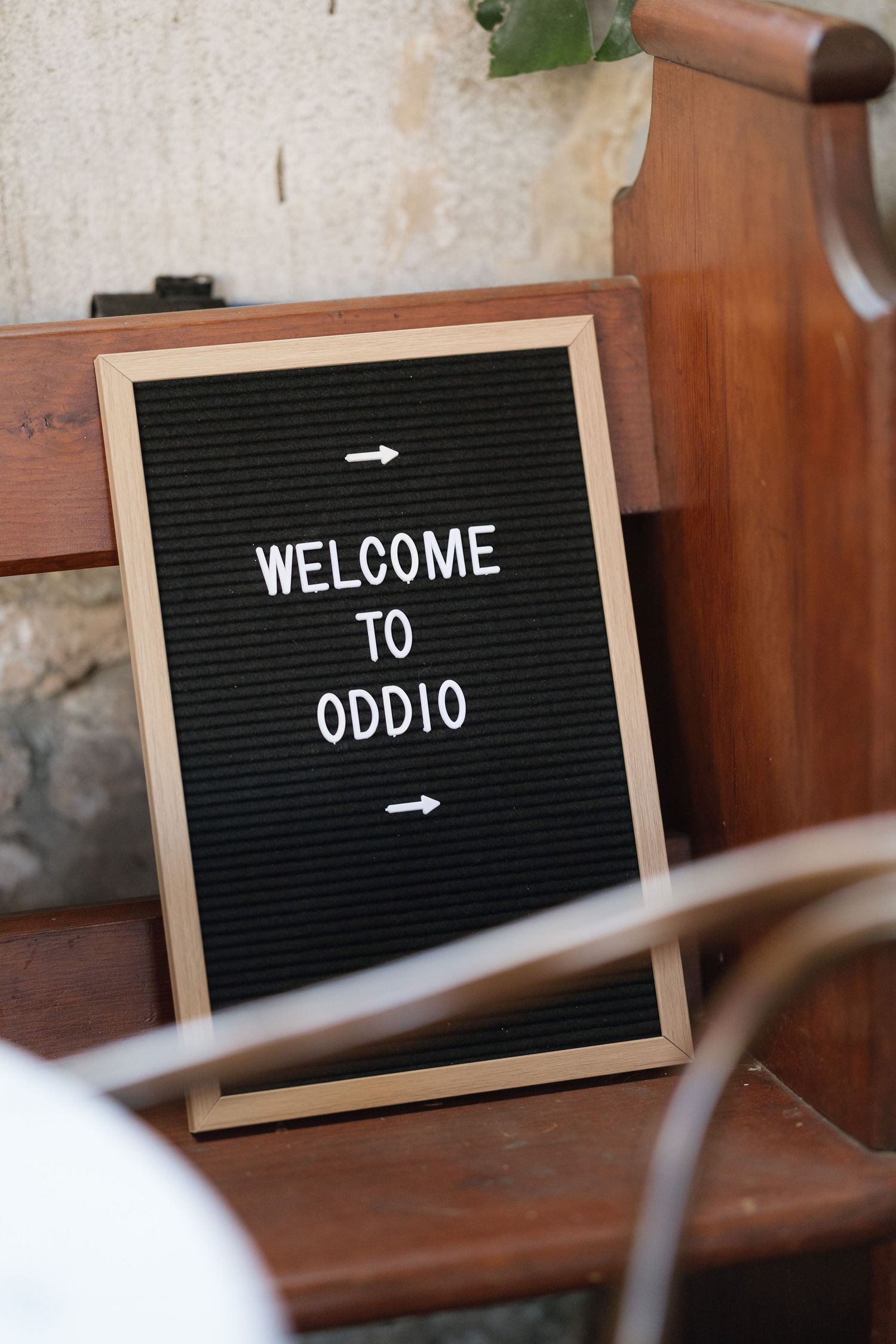 Welcome to Oddio letter board sign with arrows displayed on wooden church pew seating.