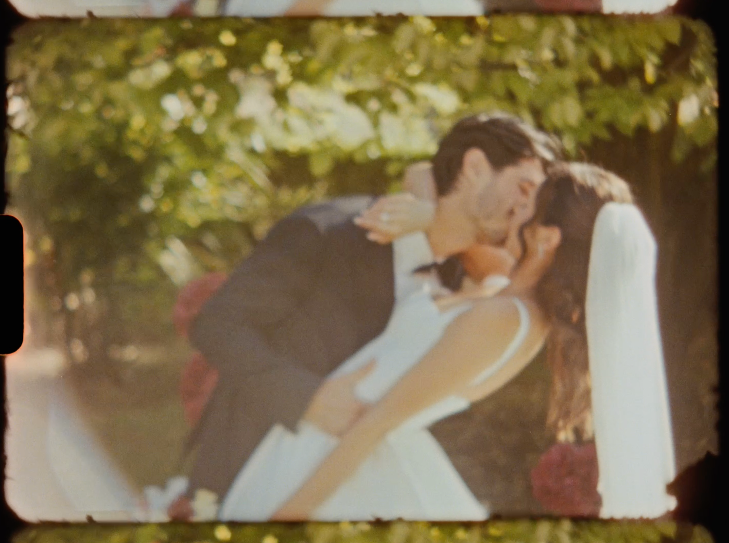 Bride and groom sharing a romantic dip kiss outdoors in a vintage film-style wedding photo.