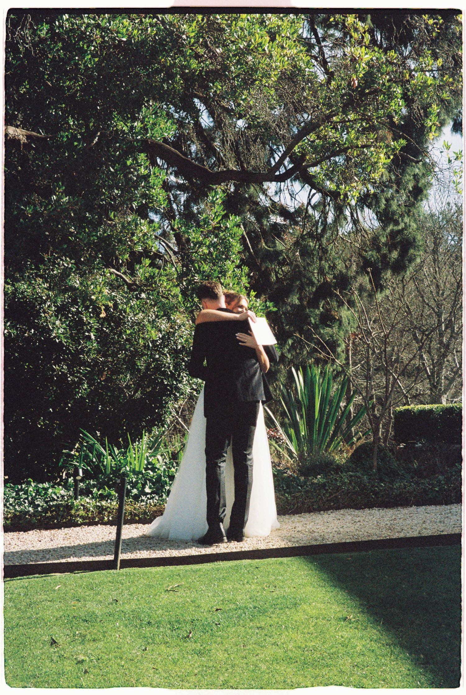 Bride and groom embrace in a lush garden setting on their wedding day.
