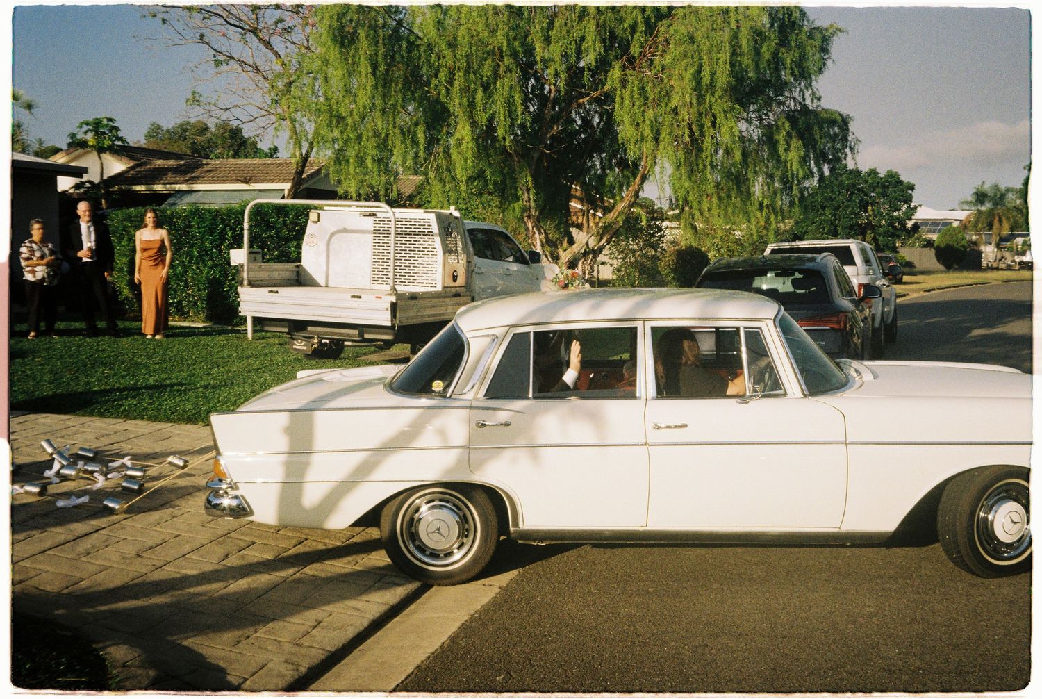 Vintage white classic car parked outside suburban home at a wedding celebration.