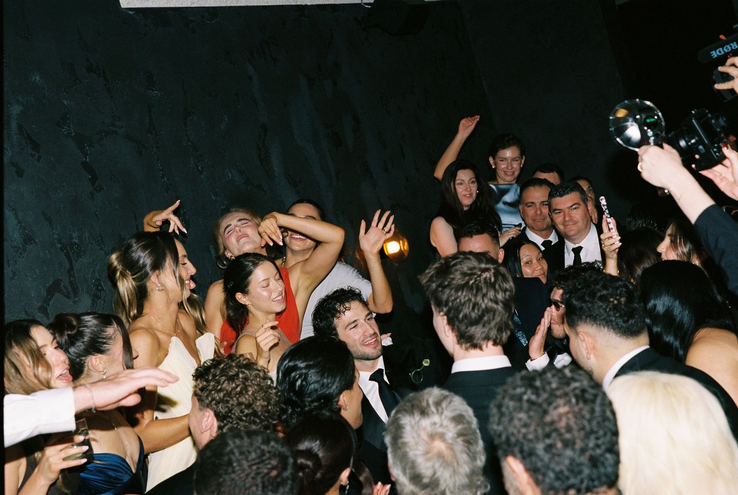 A lively crowd of wedding guests dance and celebrate on a packed dance floor.