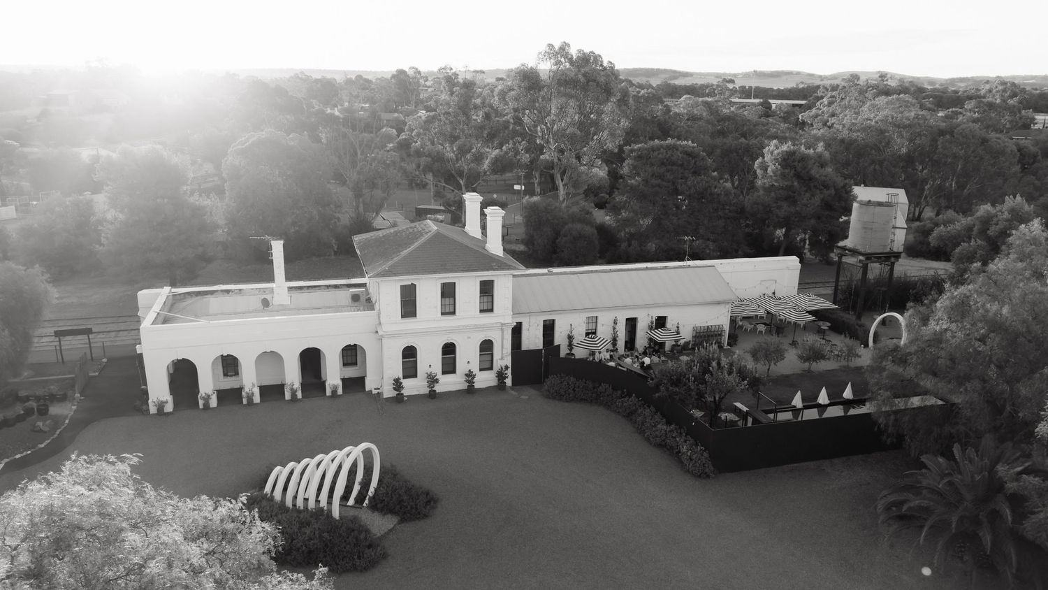 Aerial black and white view of a grand historic estate surrounded by lush trees and manicured grounds.