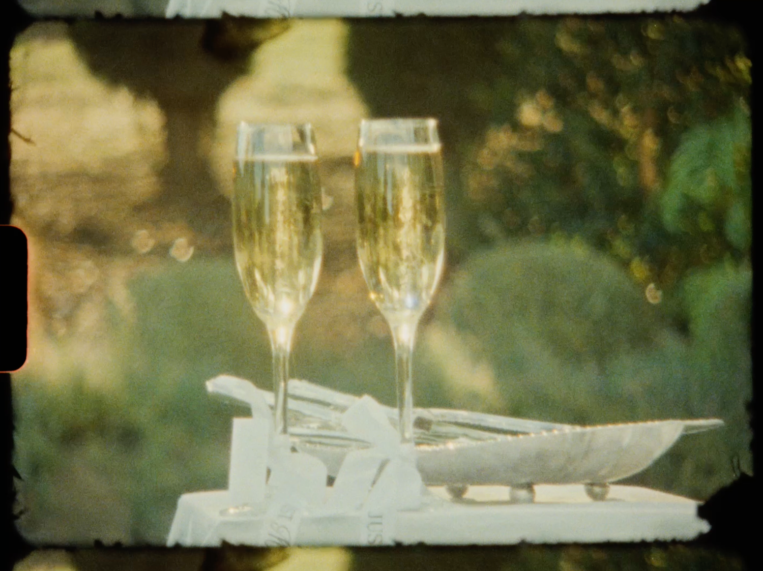 Two champagne flutes filled with sparkling wine beside a cake knife set at wedding.