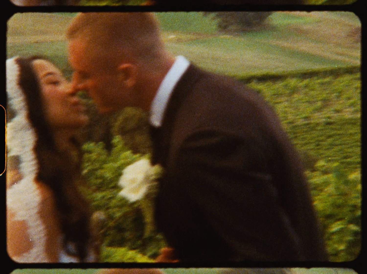 Newlyweds kissing tenderly with lush vineyard landscape visible behind them on their wedding day.