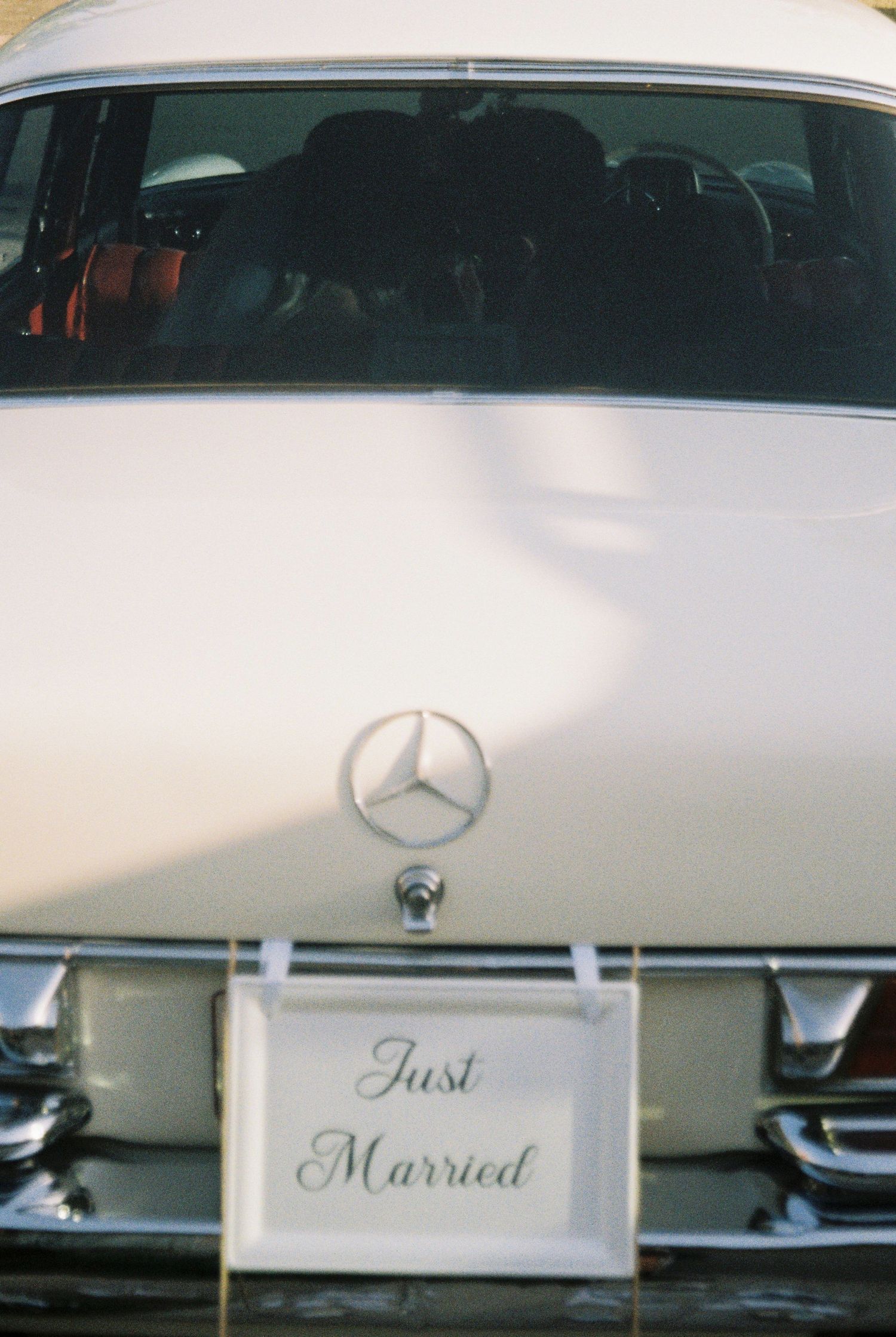 Vintage white Mercedes-Benz wedding car with Just Married sign attached to rear bumper.